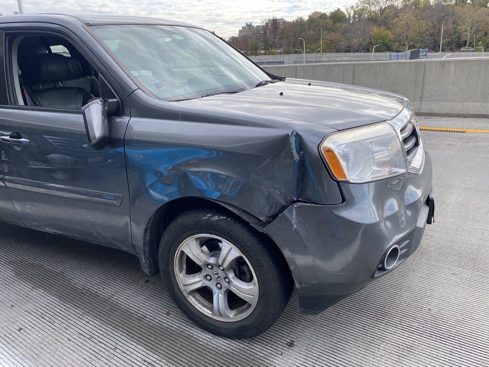 Grey SUV with damage near the front wheel before repair