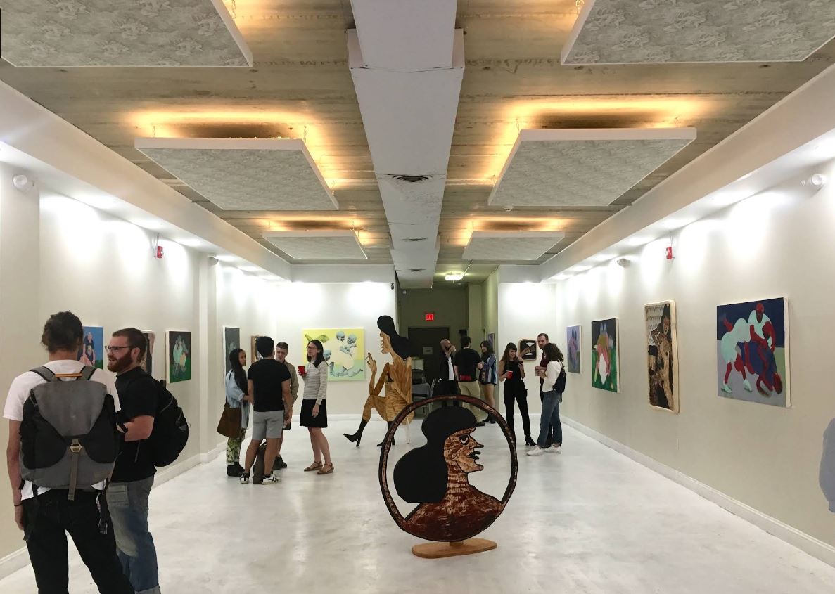 Visitors exploring artwork displayed along the walls of Open Space