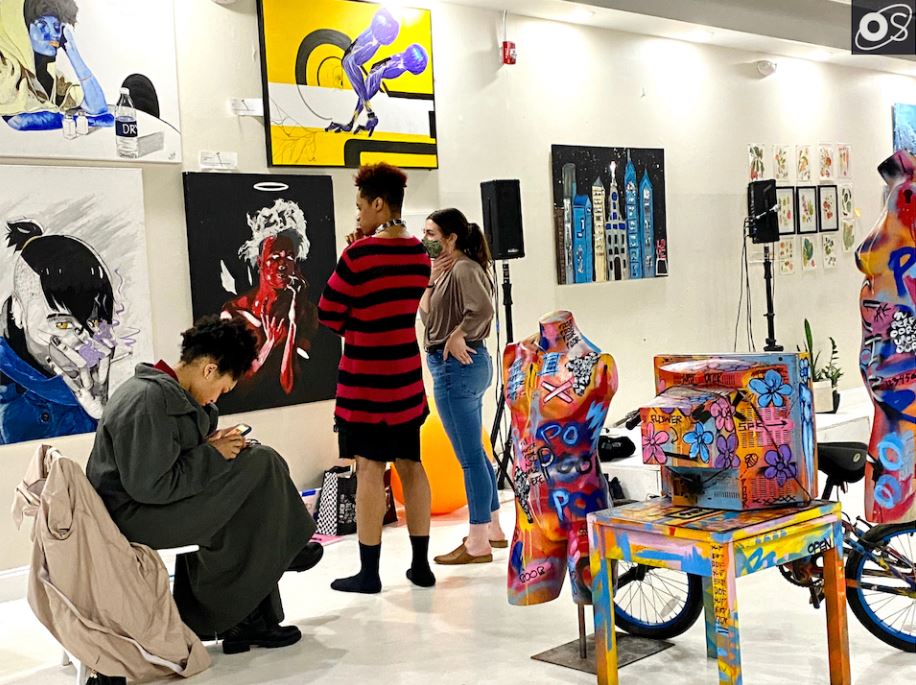 An artist at work surrounded by paintings in Open Space