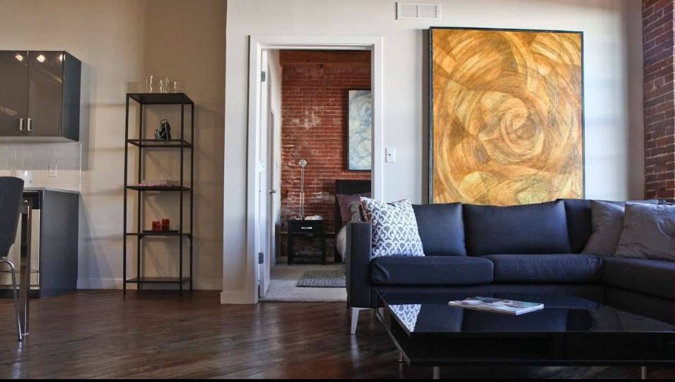 Living space with dark sofa, tall windows and exposed architectural details