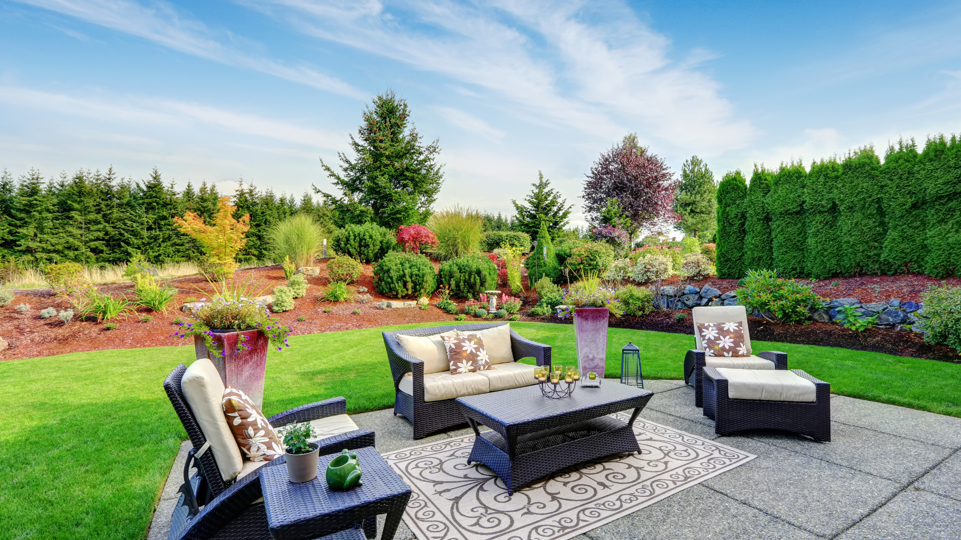 Patio seating area with outdoor furniture surrounded by garden beds — patio installation by Oak and Stone Landscaping