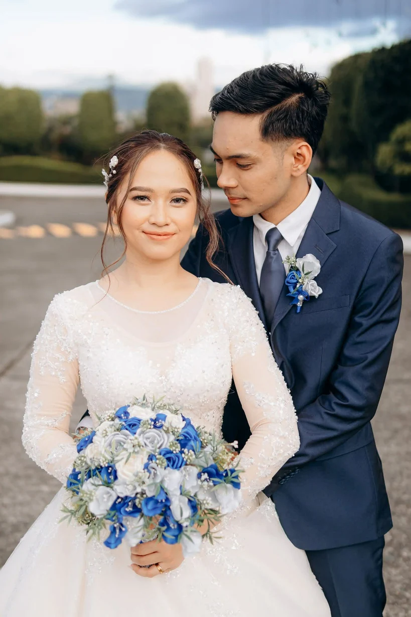 Bride holding custom blue and white wedding flowers alongside her groom