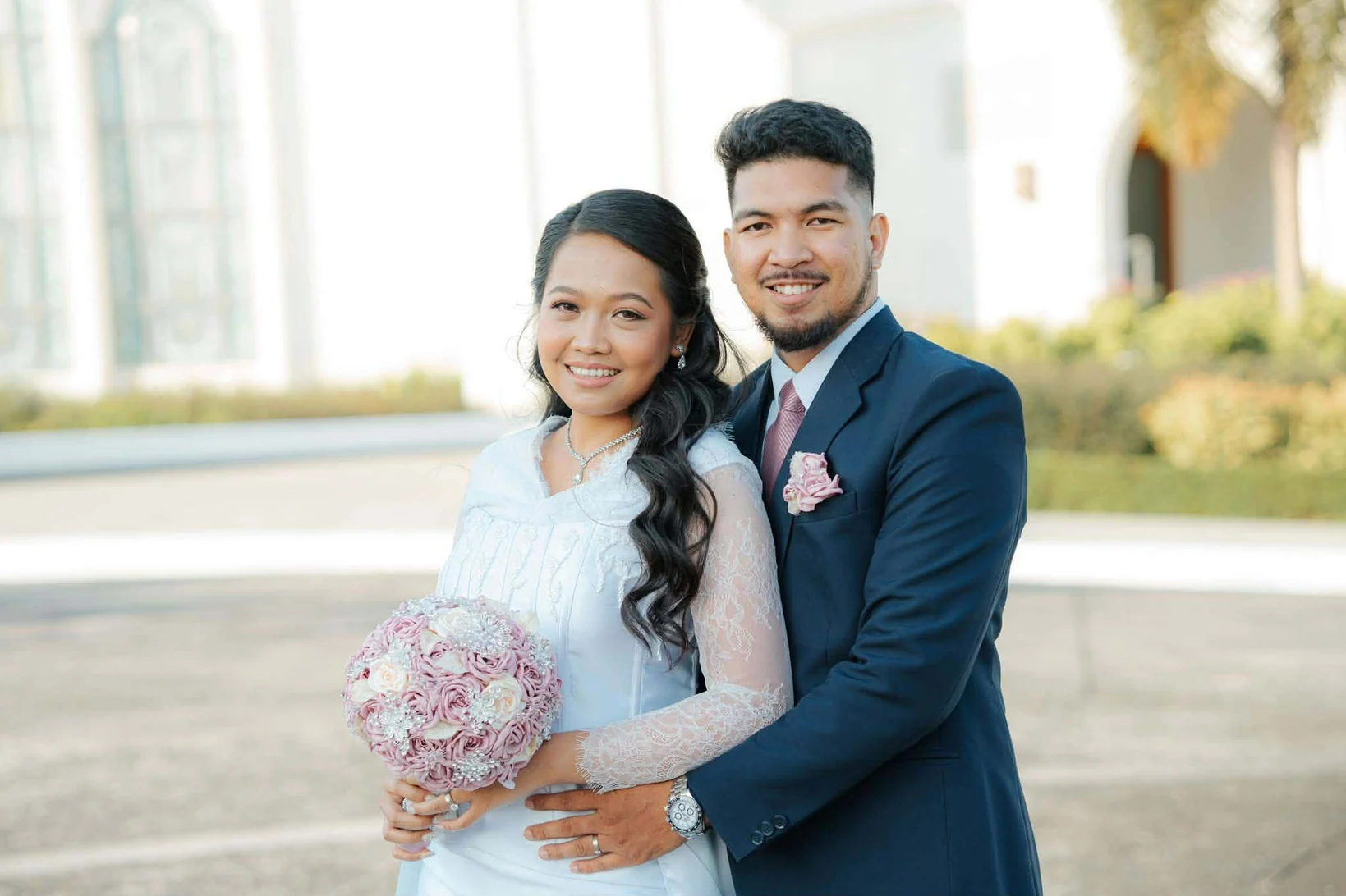 Newly married couple holding a custom pink floral bouquet