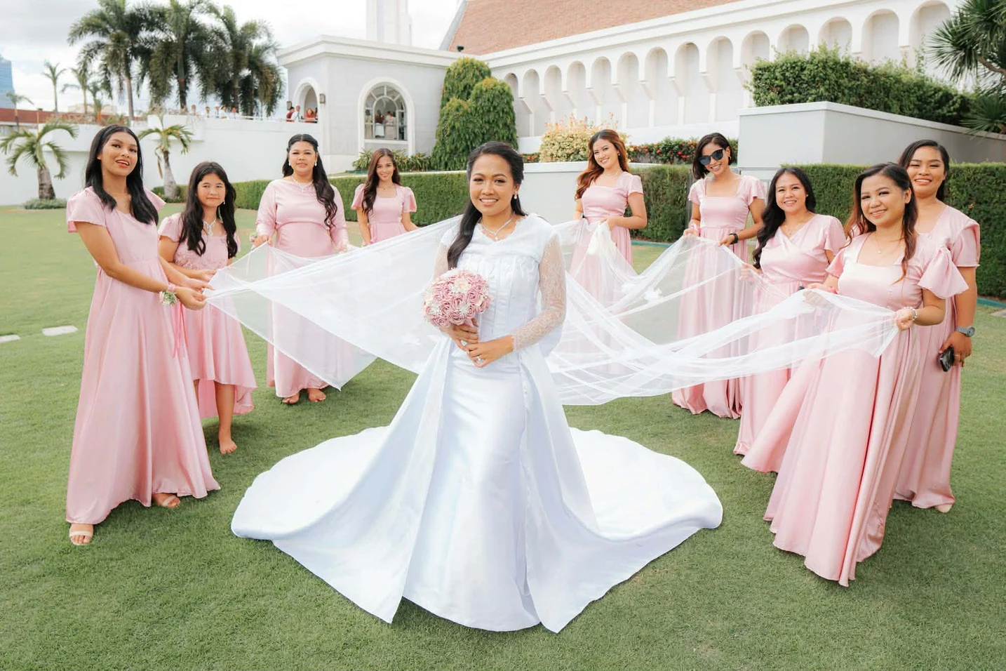Bride and wedding entourage wearing blush pink dresses outdoors