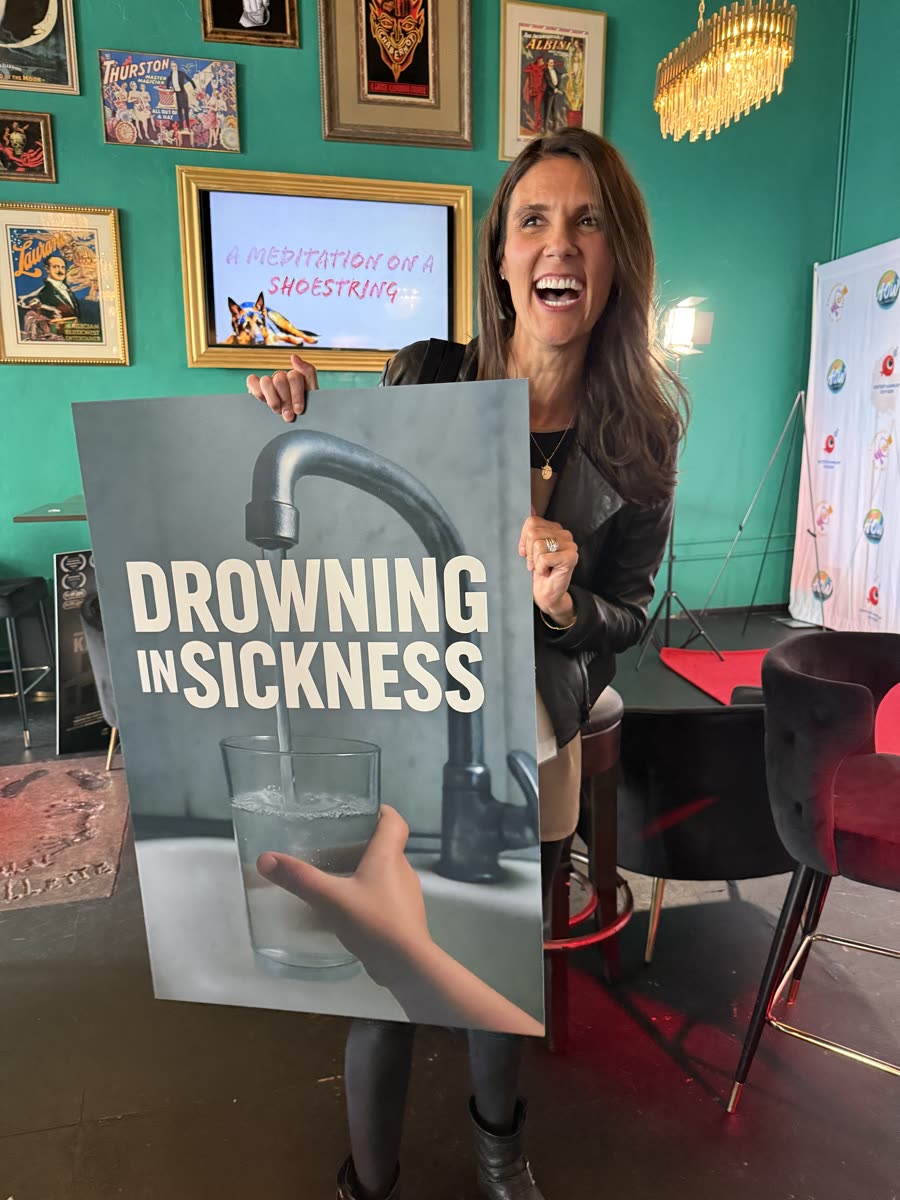 Jane Box smiling and holding the Drowning in Sickness poster