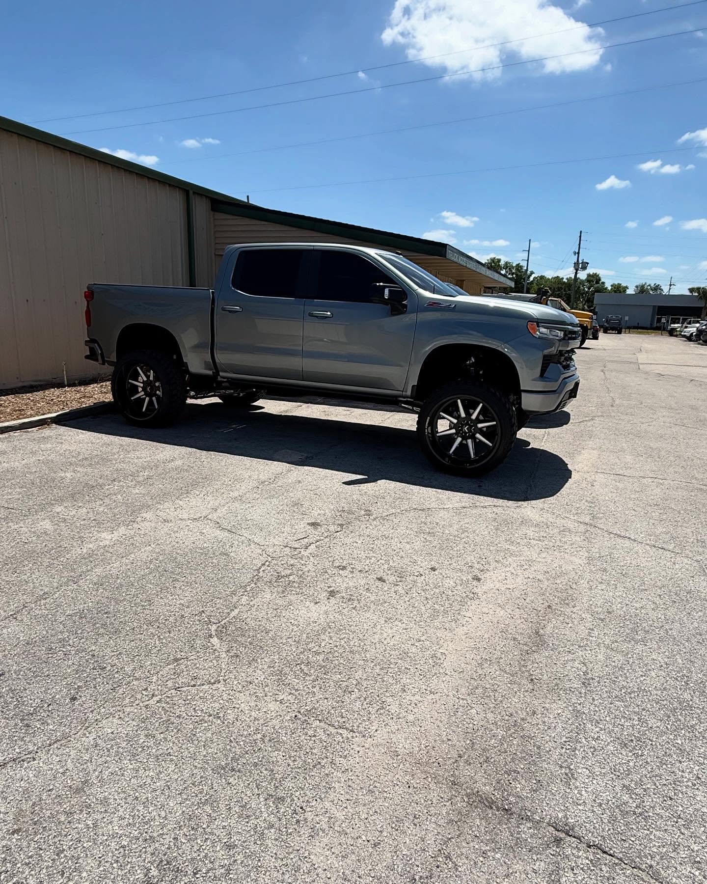 Lifted gray Chevy Silverado outside the Top Trucks shop