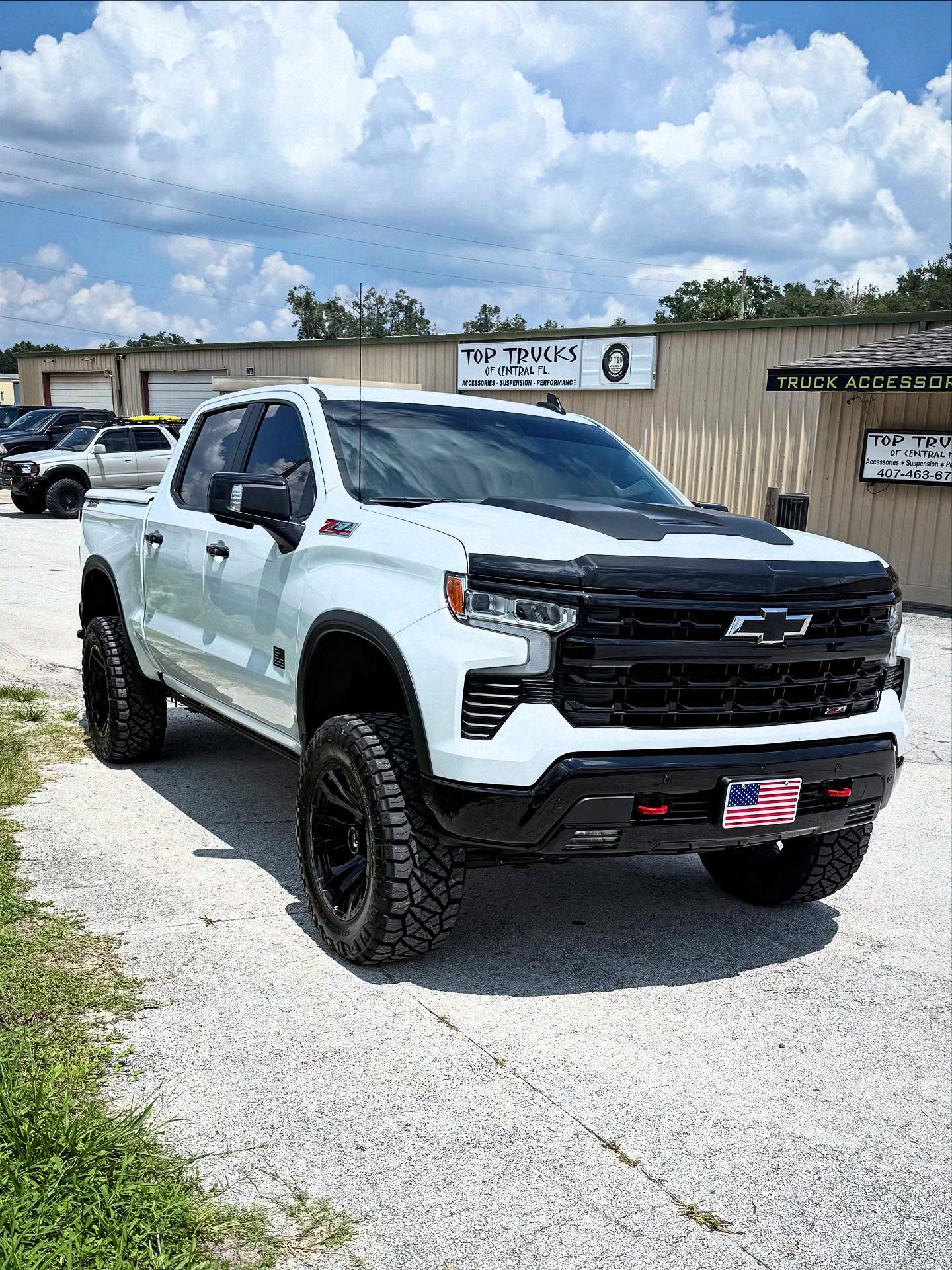 Lifted white Chevy Silverado 1500 outside the Top Trucks shop