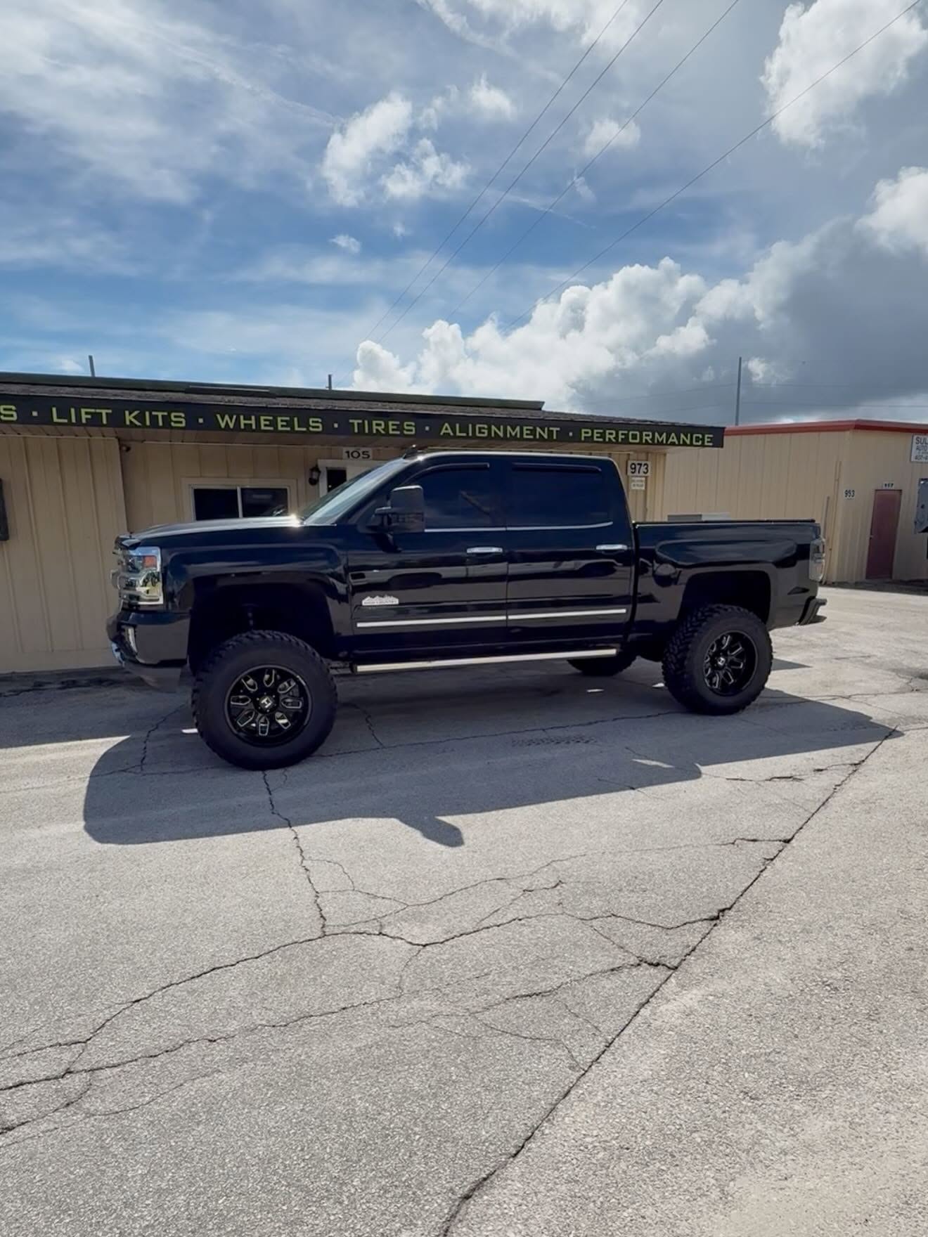 Lifted dark Chevy Silverado HD outside the Top Trucks shop