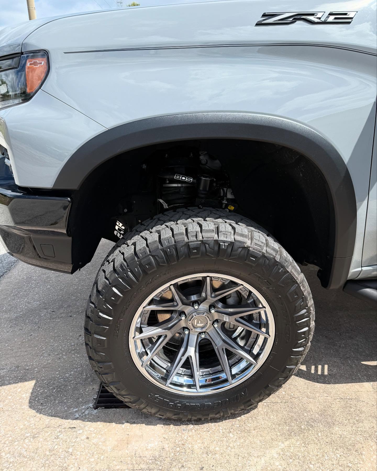 Lifted Chevy with an all-terrain wheel and tire under the fender