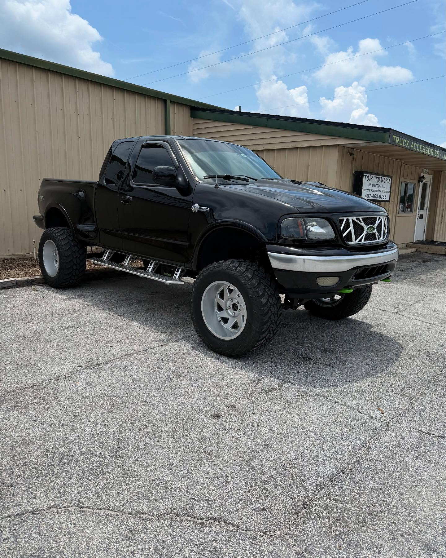 Lifted classic black Ford pickup outside the Top Trucks shop