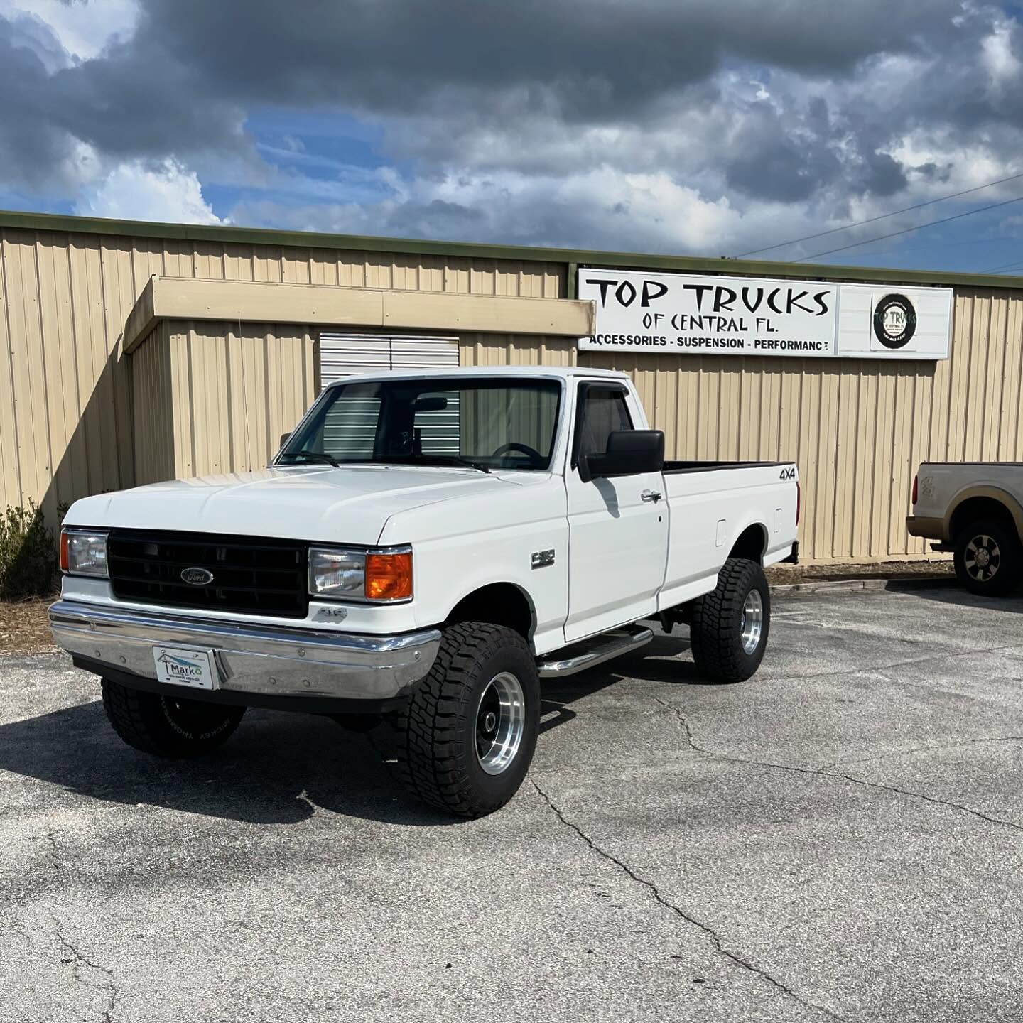 Lifted classic white Ford pickup outside the Top Trucks shop