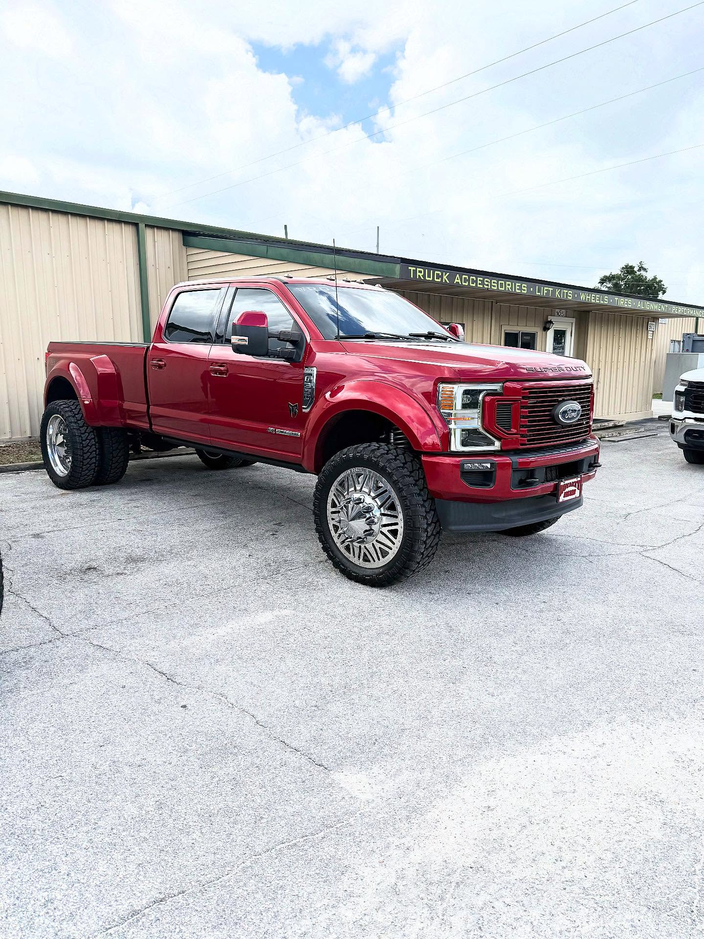 Lifted red Ford F-350 dually outside the Top Trucks shop