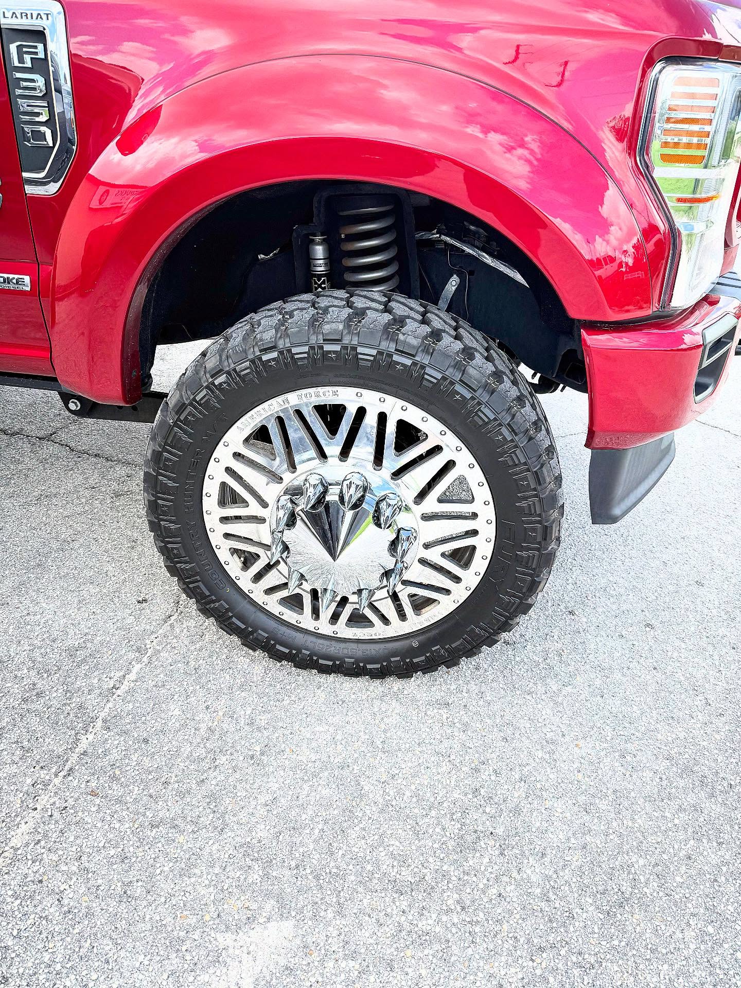 Machined chrome wheel and off-road tire on a lifted red truck