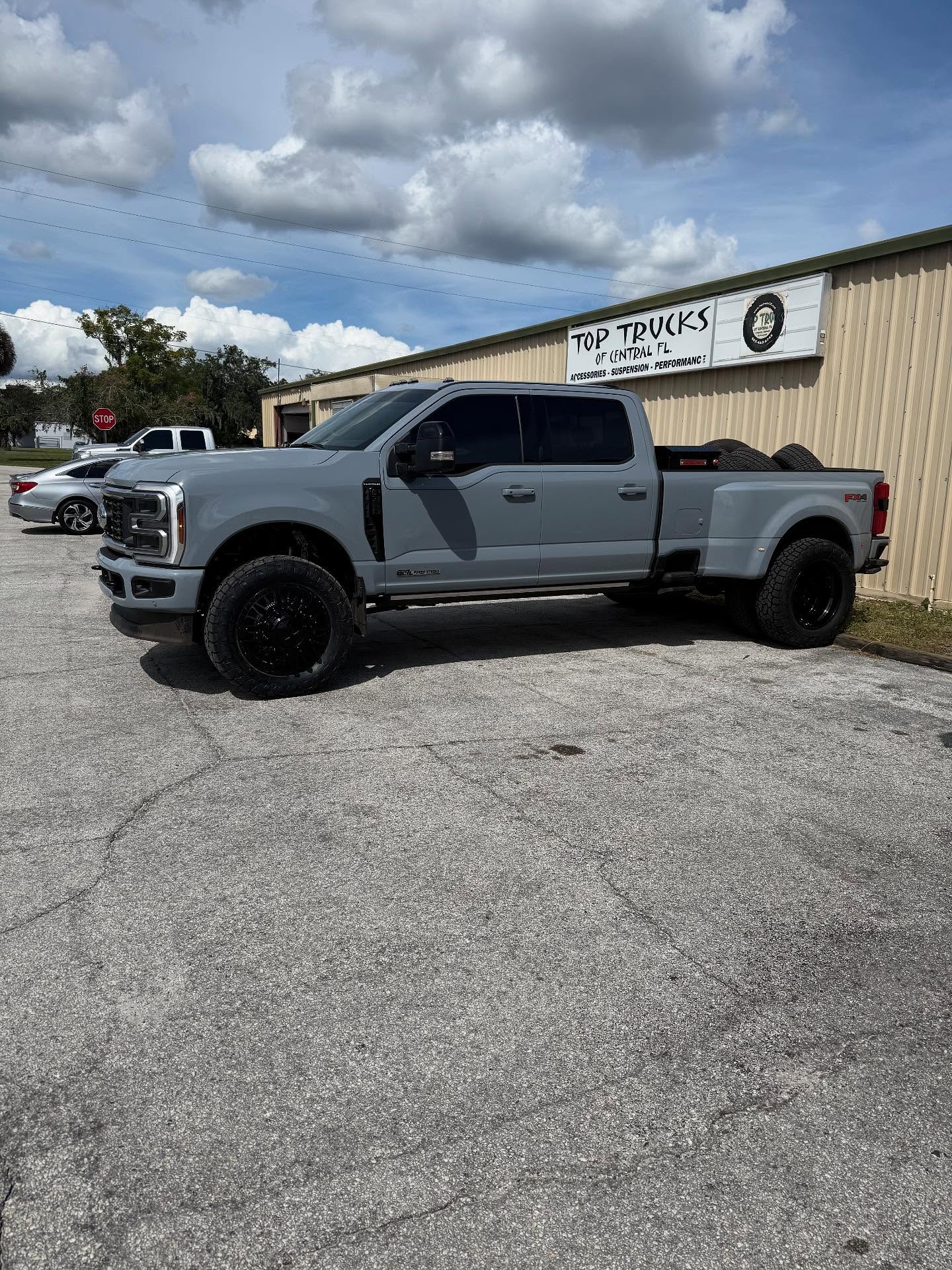 Lifted gray Ford Super Duty dually outside the Top Trucks shop