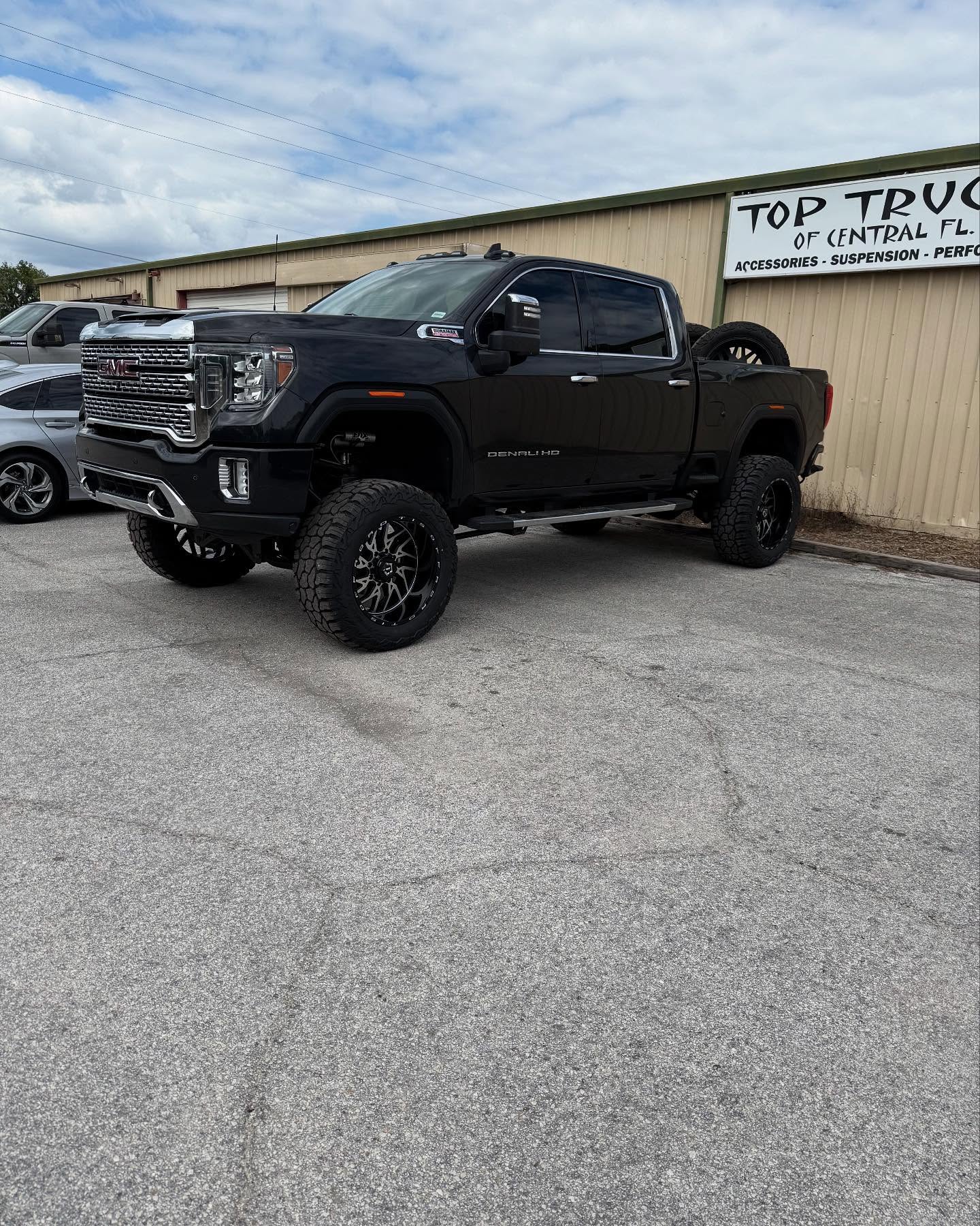 Lifted black GMC Sierra HD outside the Top Trucks shop