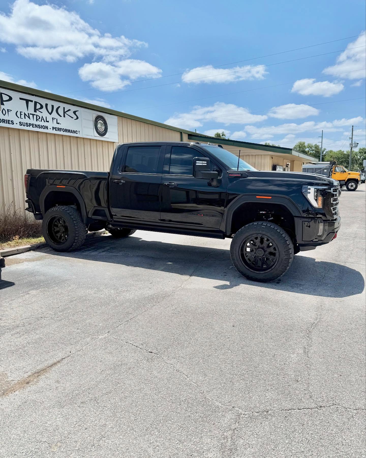 Lifted black GMC Sierra Denali HD outside the Top Trucks shop