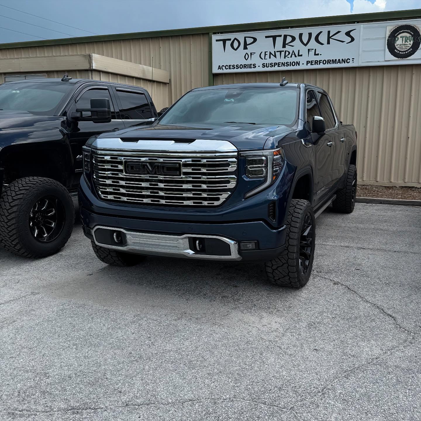 Lifted navy GMC Sierra Denali outside the Top Trucks shop