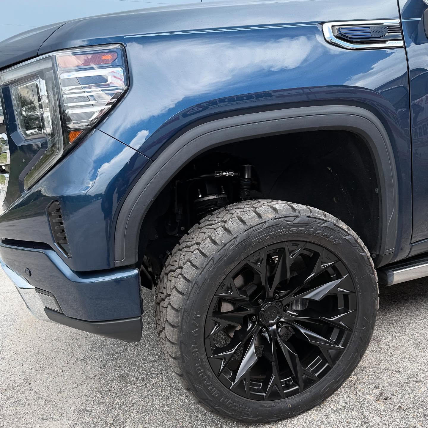 Blue GMC Sierra wheel, up close, built at Top Trucks of Central Florida in Longwood, FL