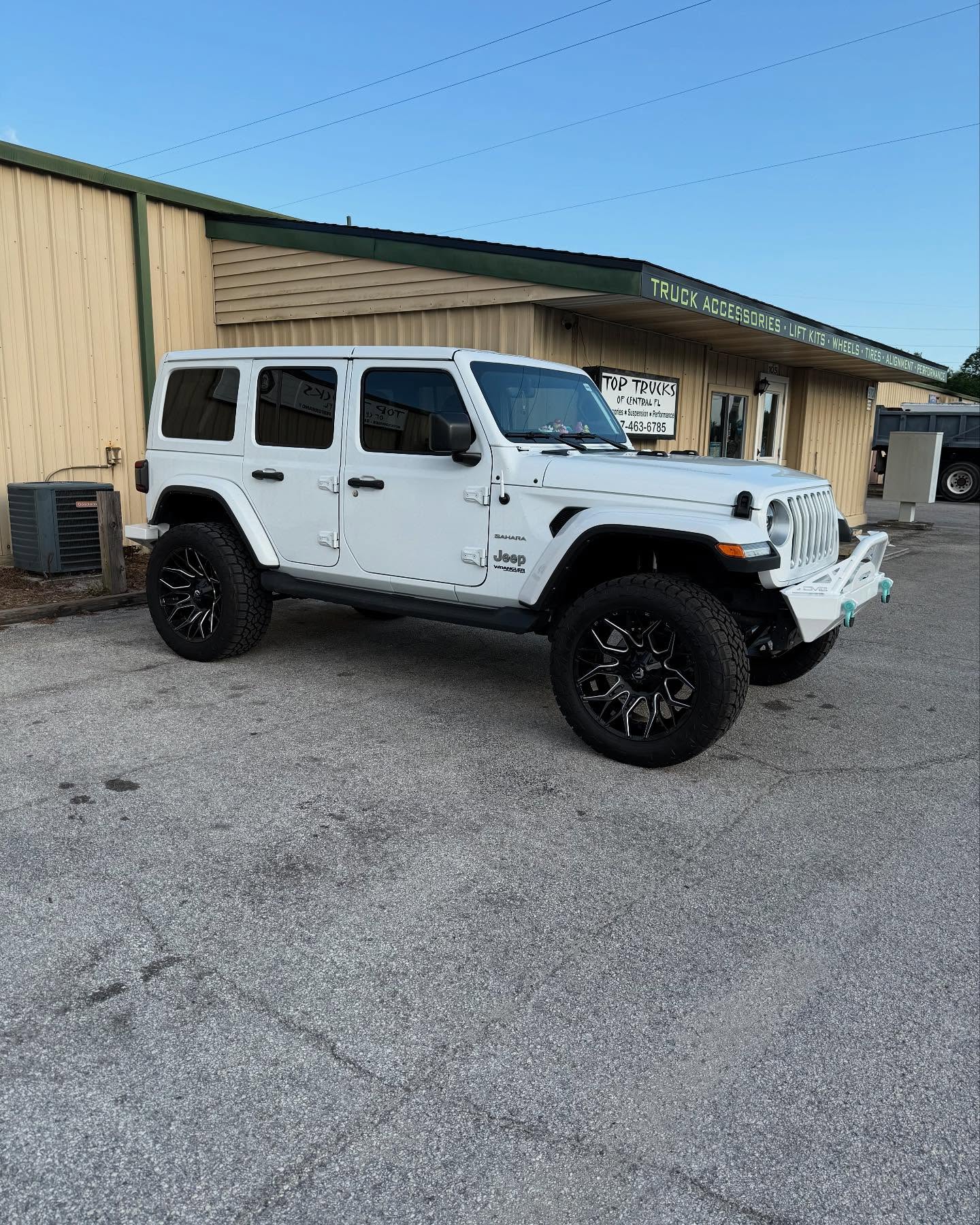 Lifted white Jeep Wrangler Unlimited outside the Top Trucks shop