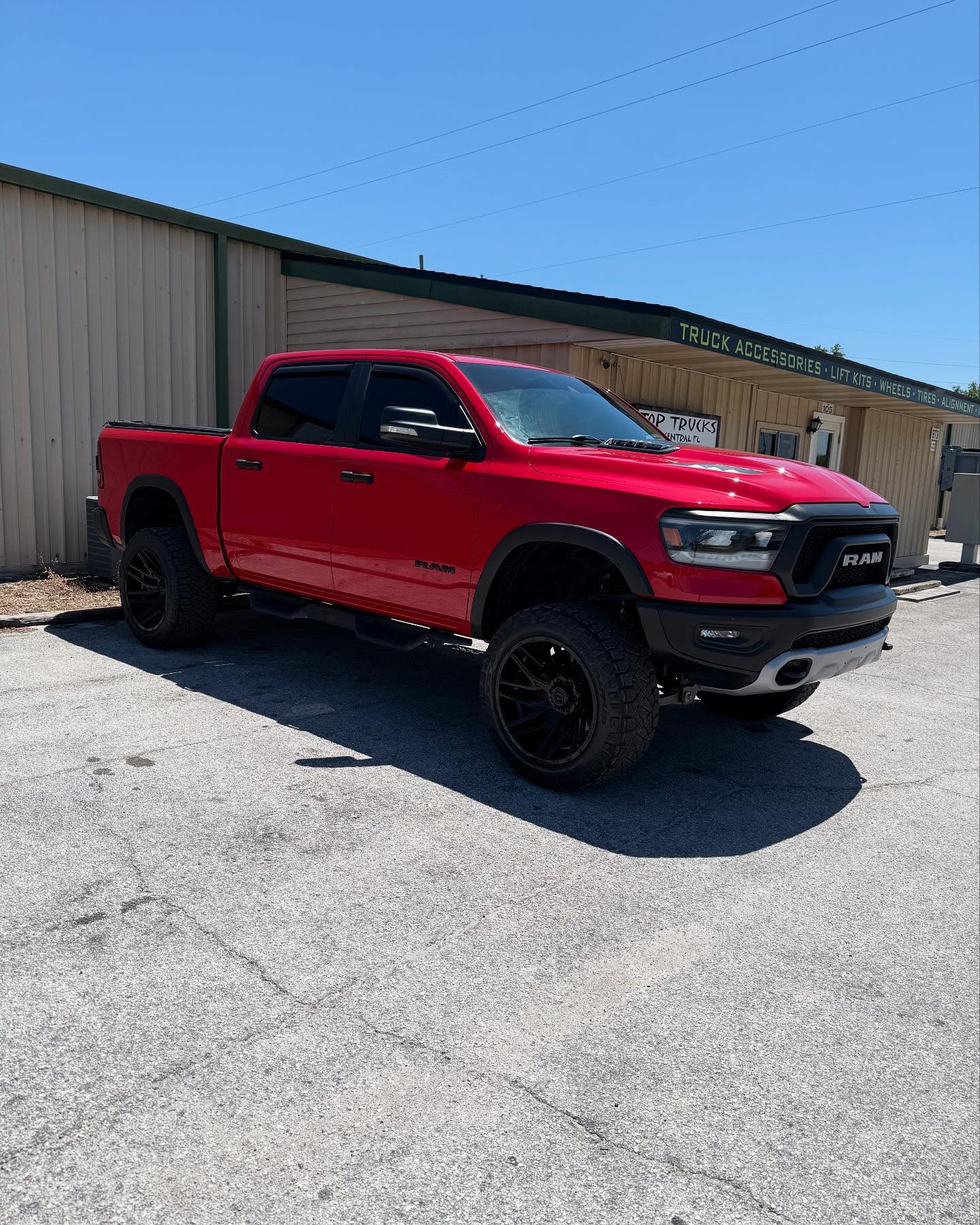 Lifted red Ram 1500 outside the Top Trucks shop