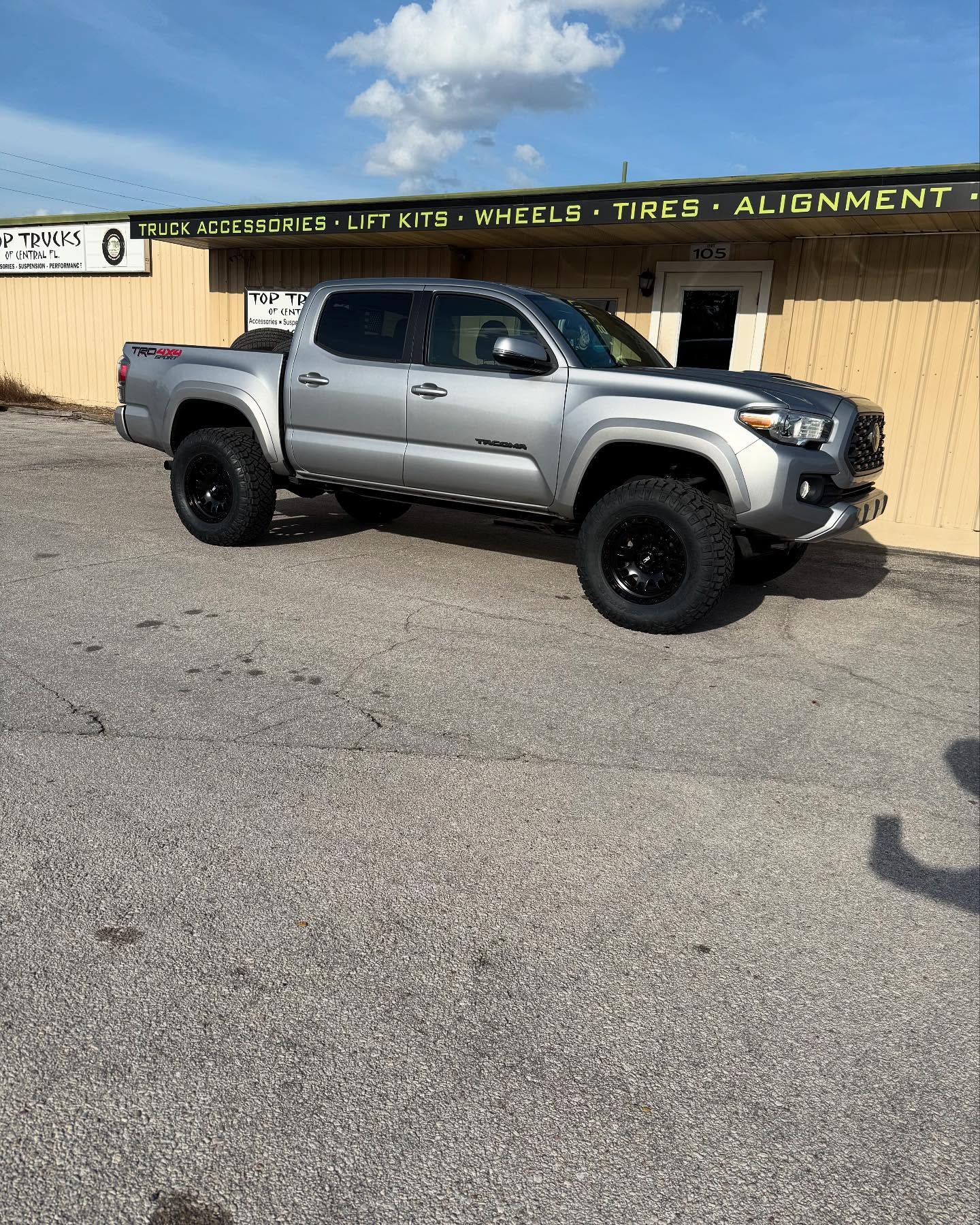 Lifted gray Toyota Tacoma outside the Top Trucks shop