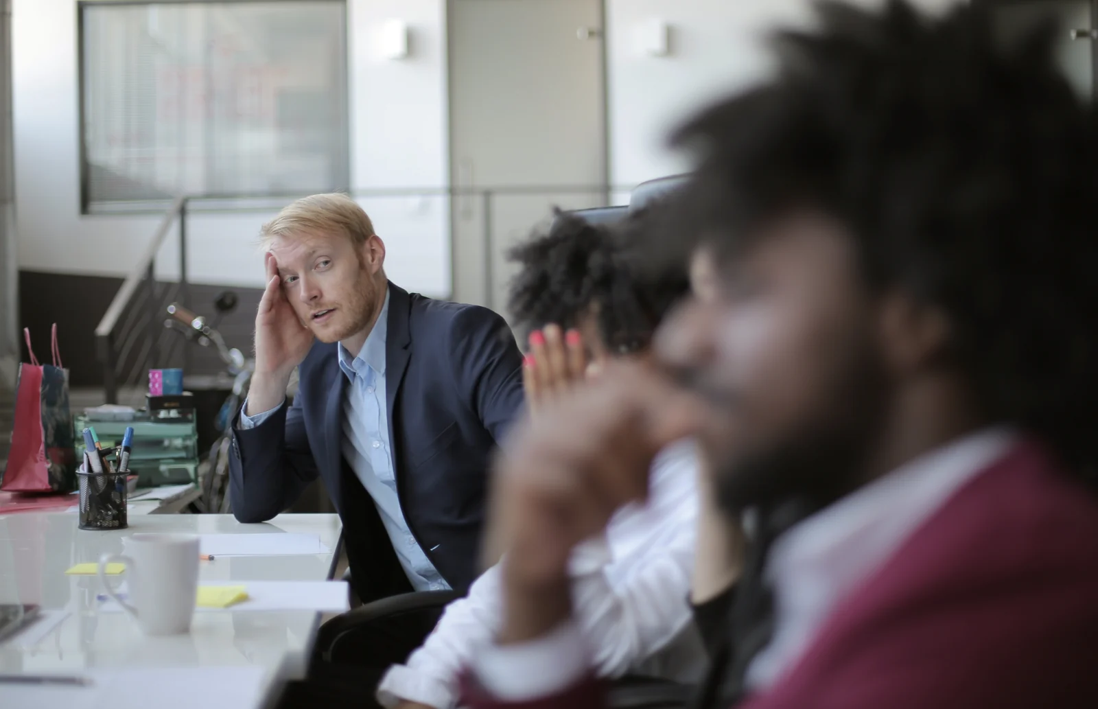 A leadership team in discussion, one person speaking while the others listen, IEXDG