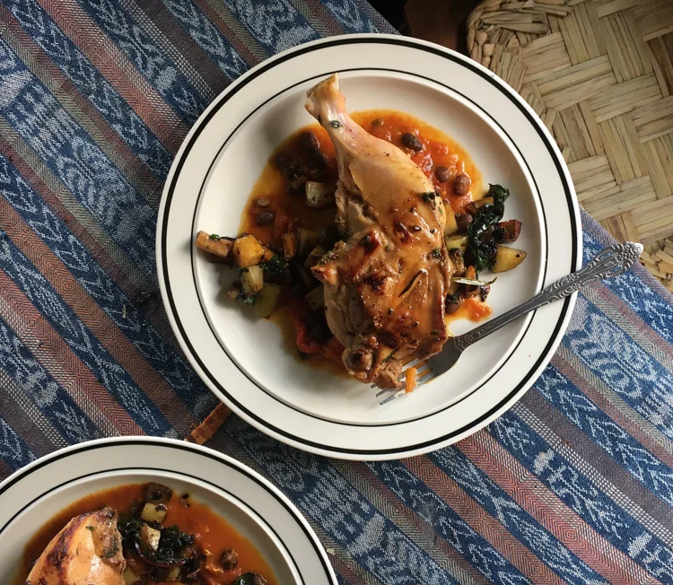 A plate of Guatemalan cuisine, featuring a chicken leg on top of greens with a yummy sauce.