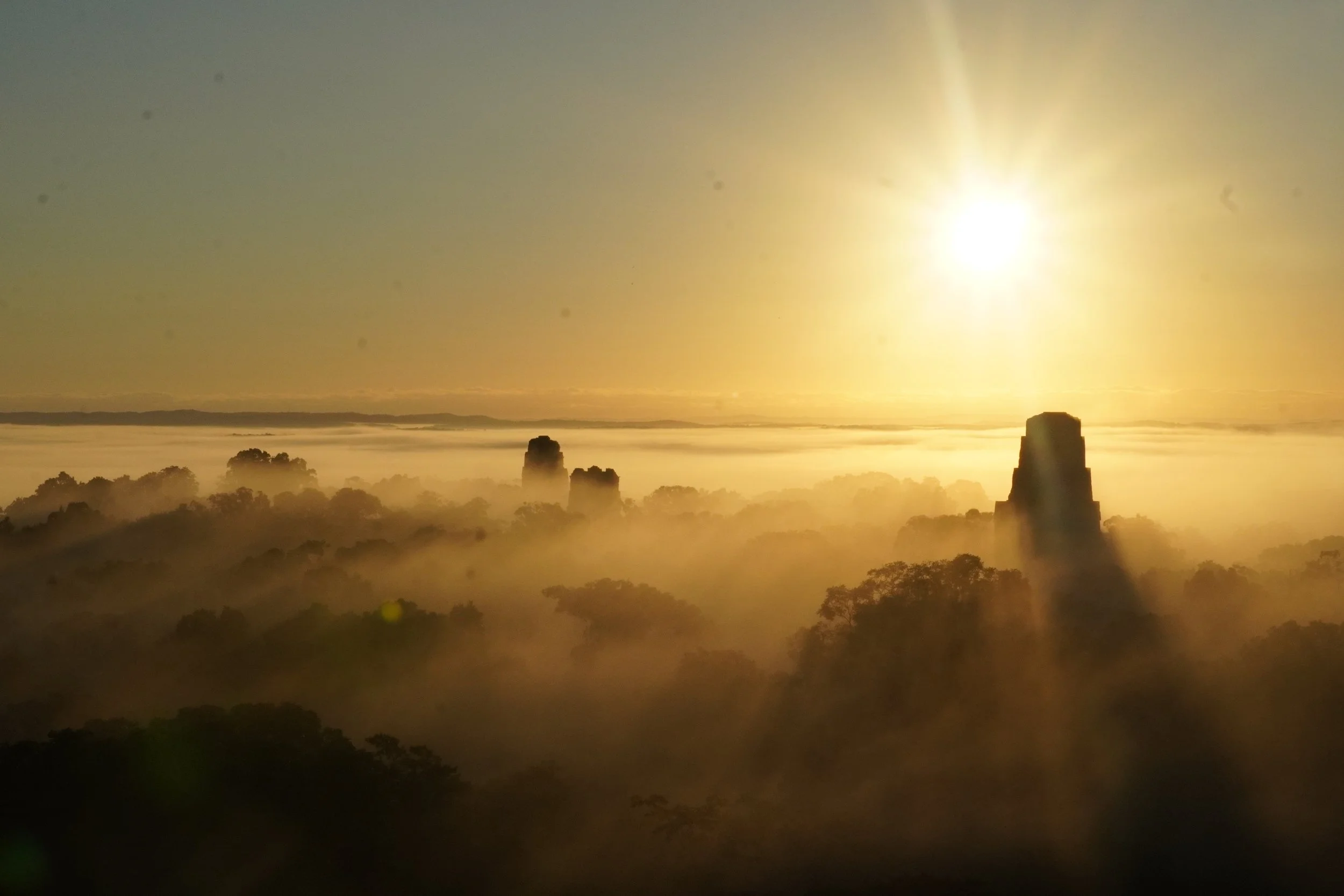 The sunrises above the clouds, forest top, and temples of Peten Guatemala