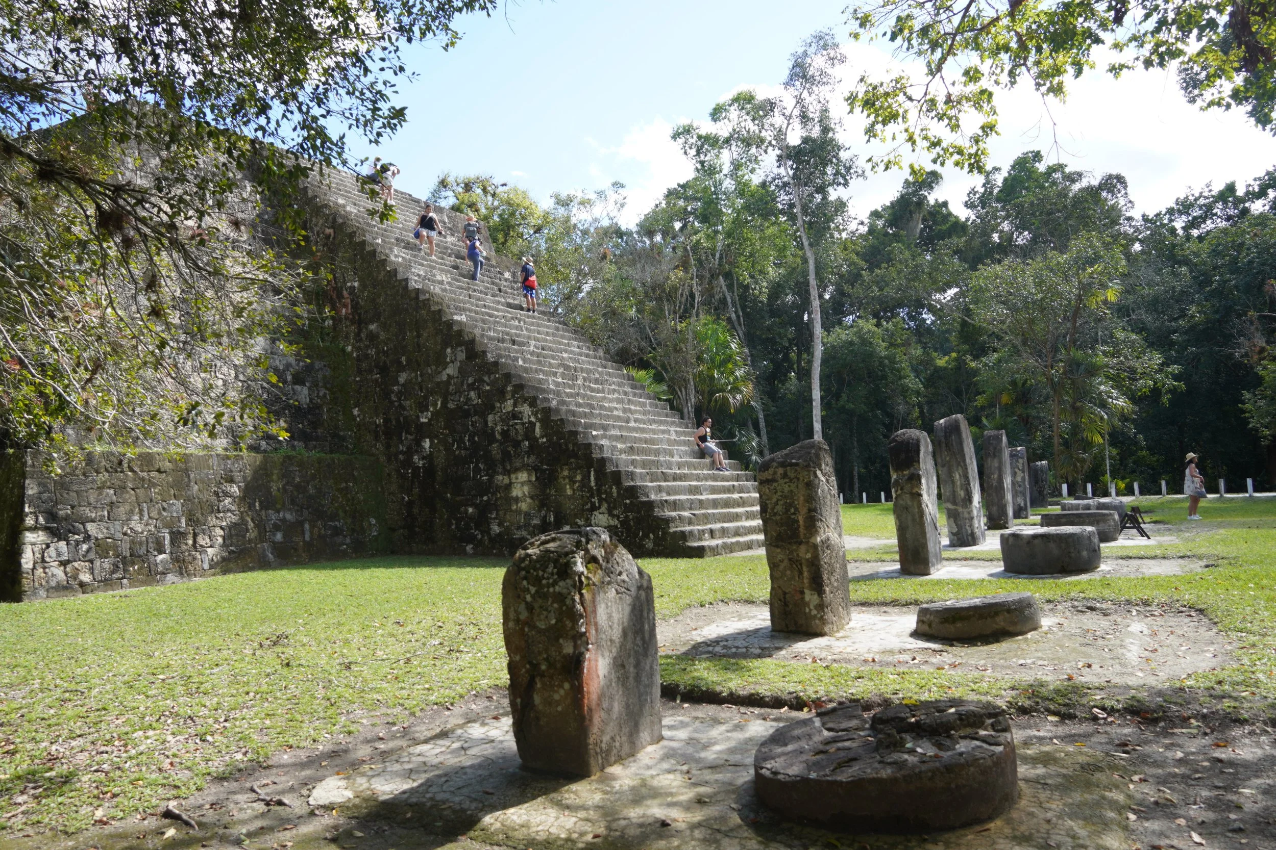 A group tour has visitors exploring the ancient steps of a tall pyramid in Tikal's National Park in the Peten Guatemala