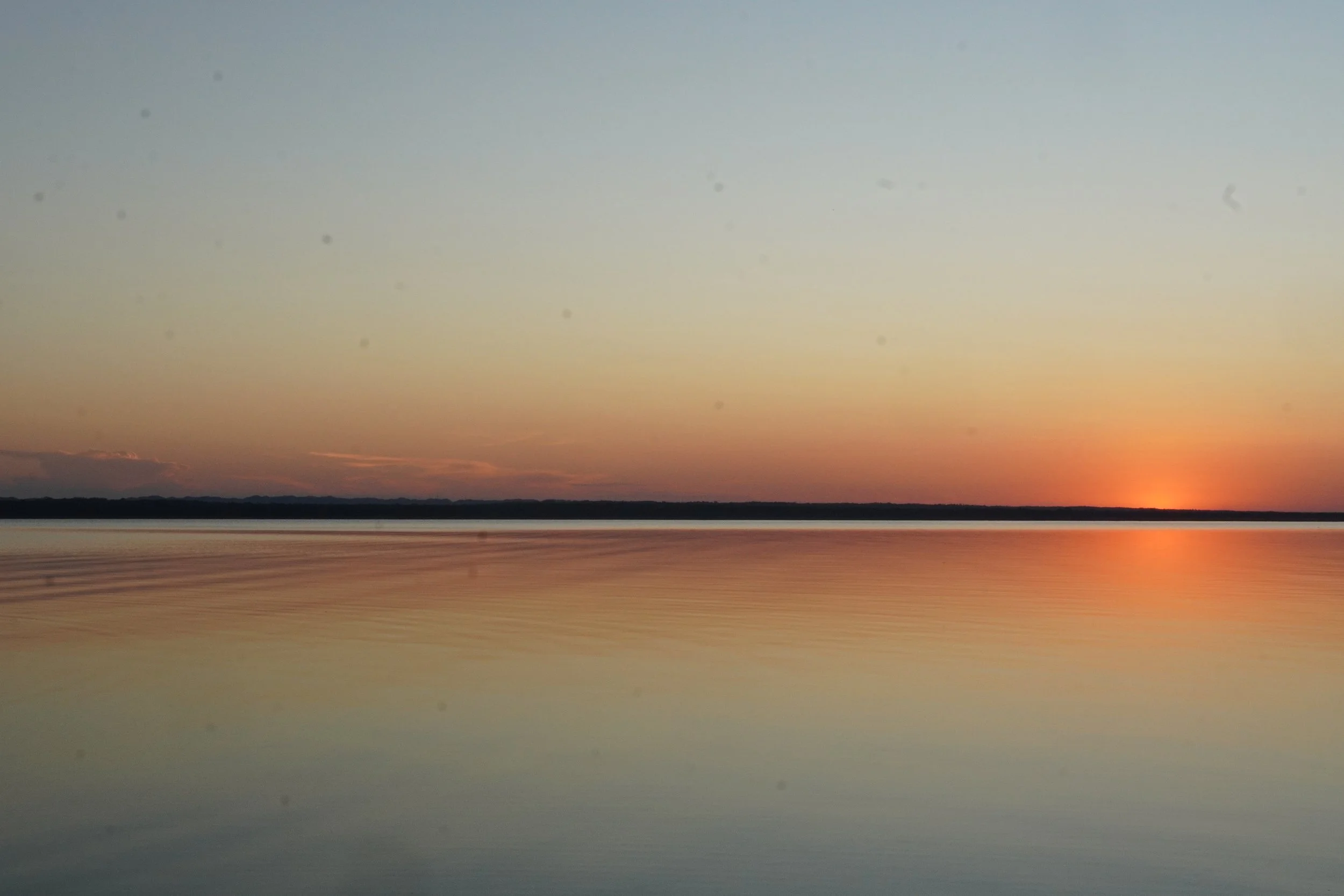 The sun sets over a calm lake in El Remate in Peten Guatemala