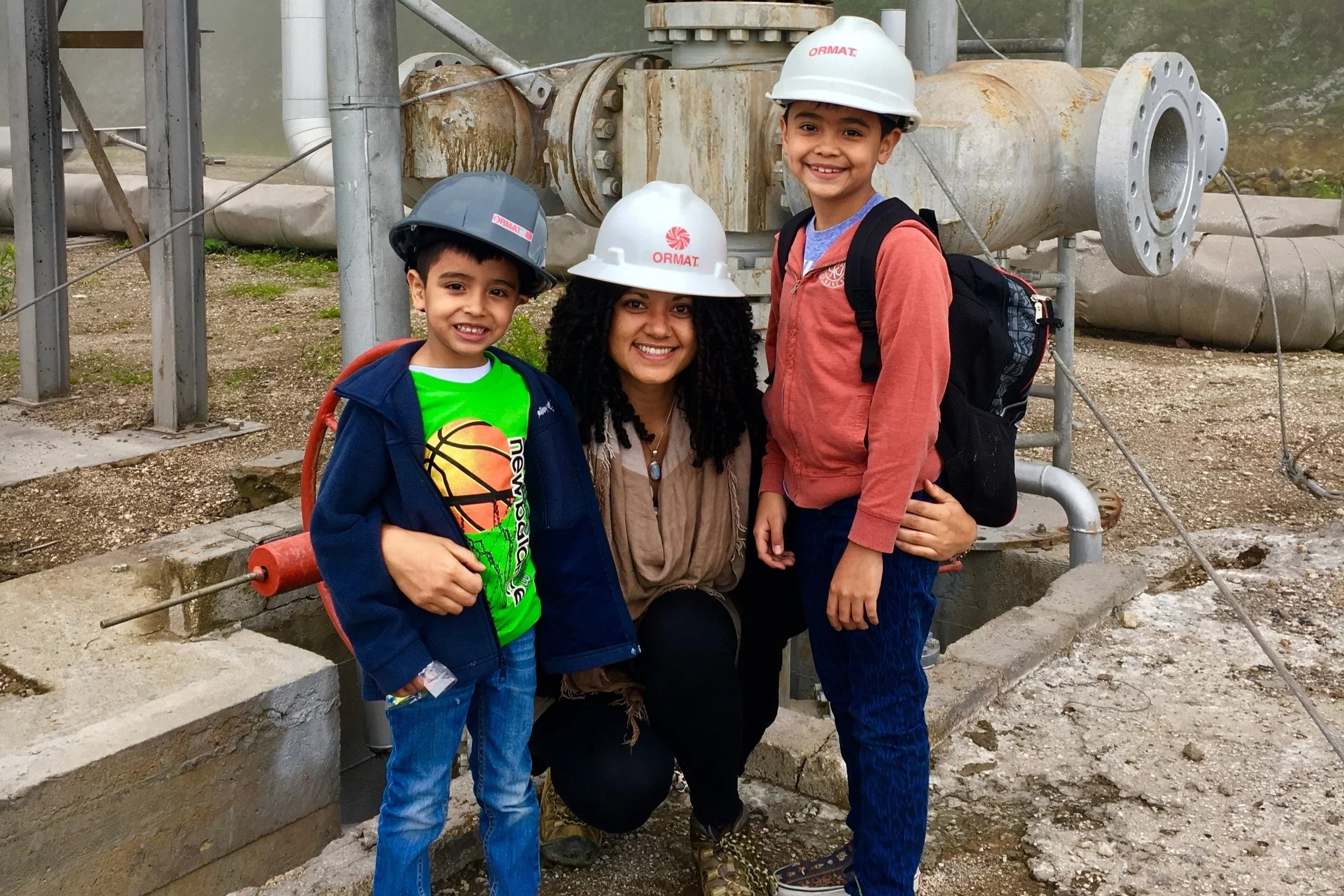 Leilani Yats, owner of NST, is wearing a hard had with two kids on a renewable energy tour