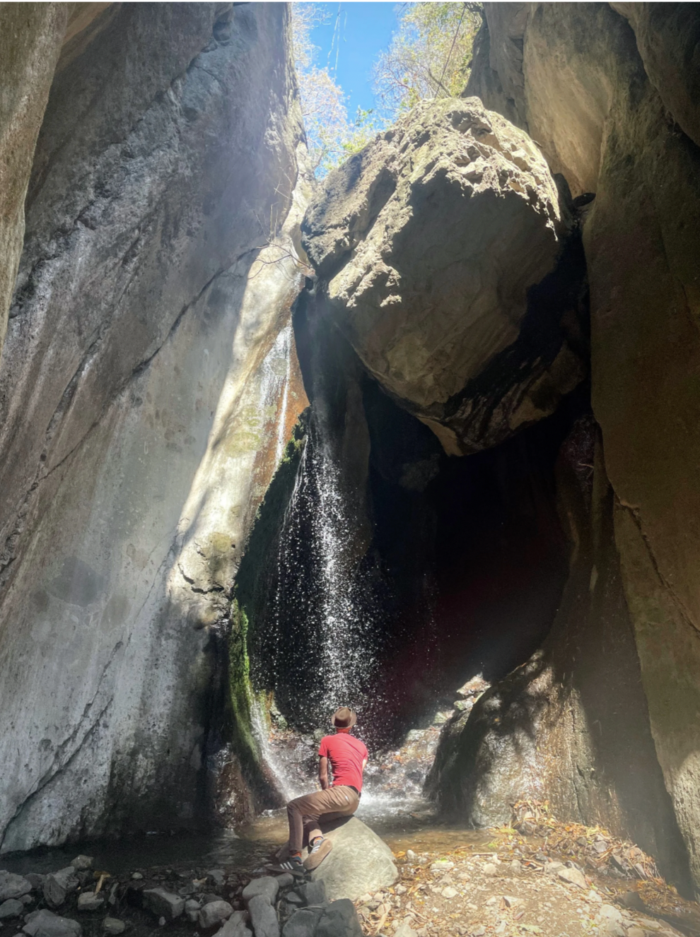 A man sits at the bottom of a waterfall and admires the beauty of nature in Guatemala.