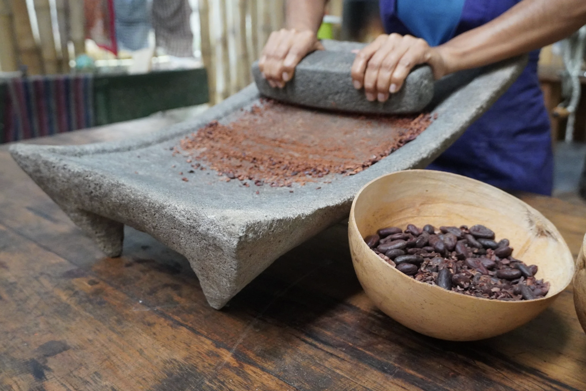 A  woman is grinding roasted cacao seeds with a stone grinder on a chocolate farm in Guatemala during the chocolate making process from bean to bar