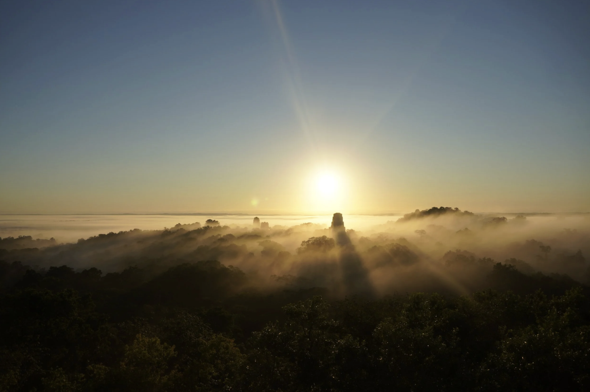 Sunrise in Tikal watching the clouds and treetops hit by the light of the sun in the Petén region of Guatemala.