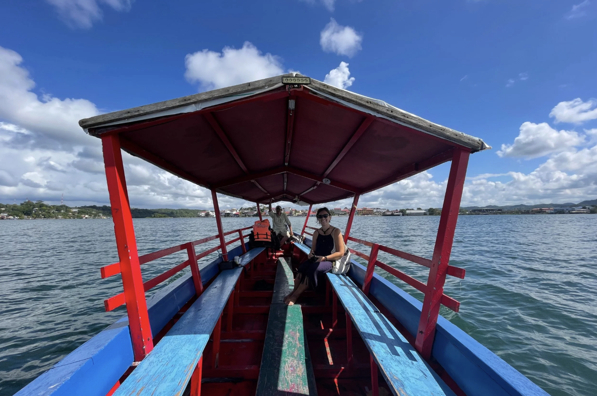 A girl sits on a boat crossing a lake on a beautiful sunny day in Petén region of Guatemala.