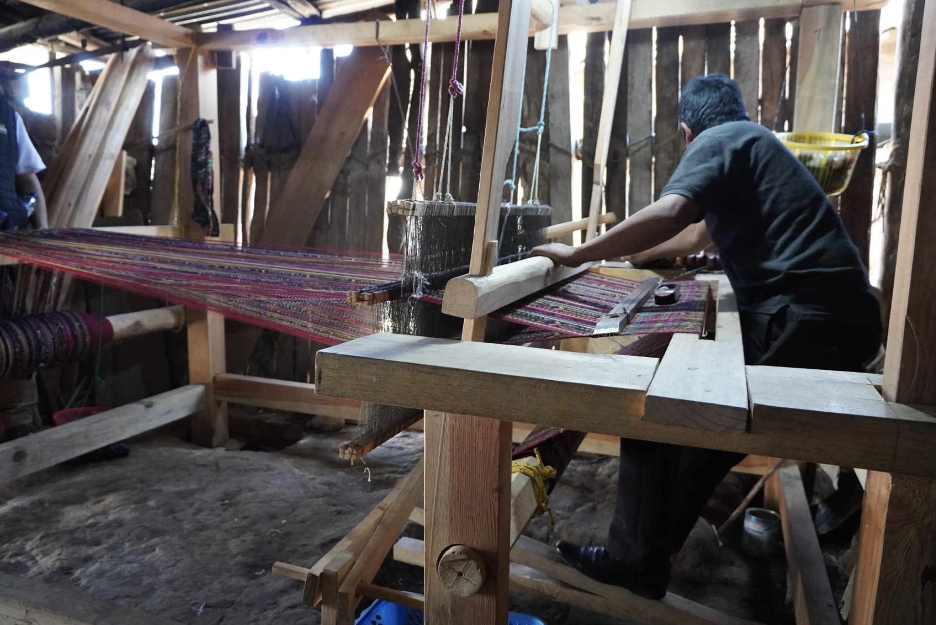 A man is working his loom in his workspace after receiving Microfinance in Latin America.