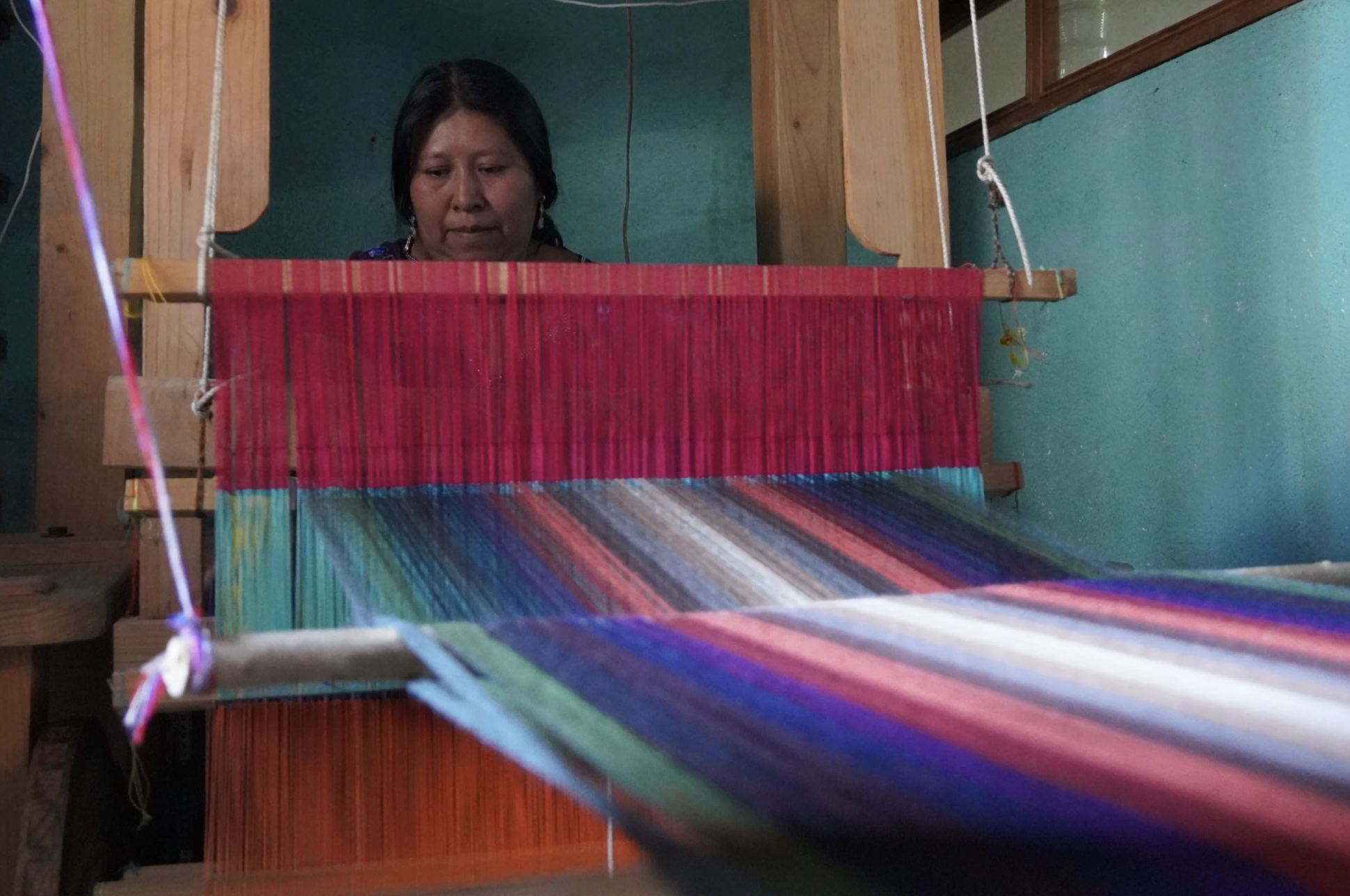 A woman in Guatemala works on her textile loom for her small business, which has benefited from Microfinance in Latin America.