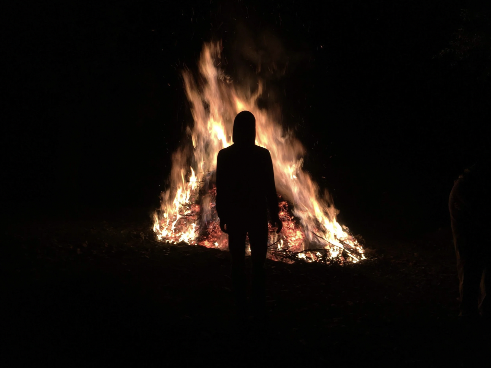 A man stands before a massive fire during a fire ceremony in Guatemala.