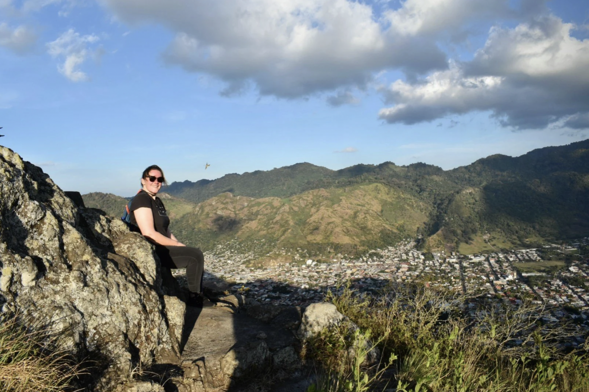 A woman is sitting on the side of a mountain enjoying the view on a hike with international student tours in Nicaragua.