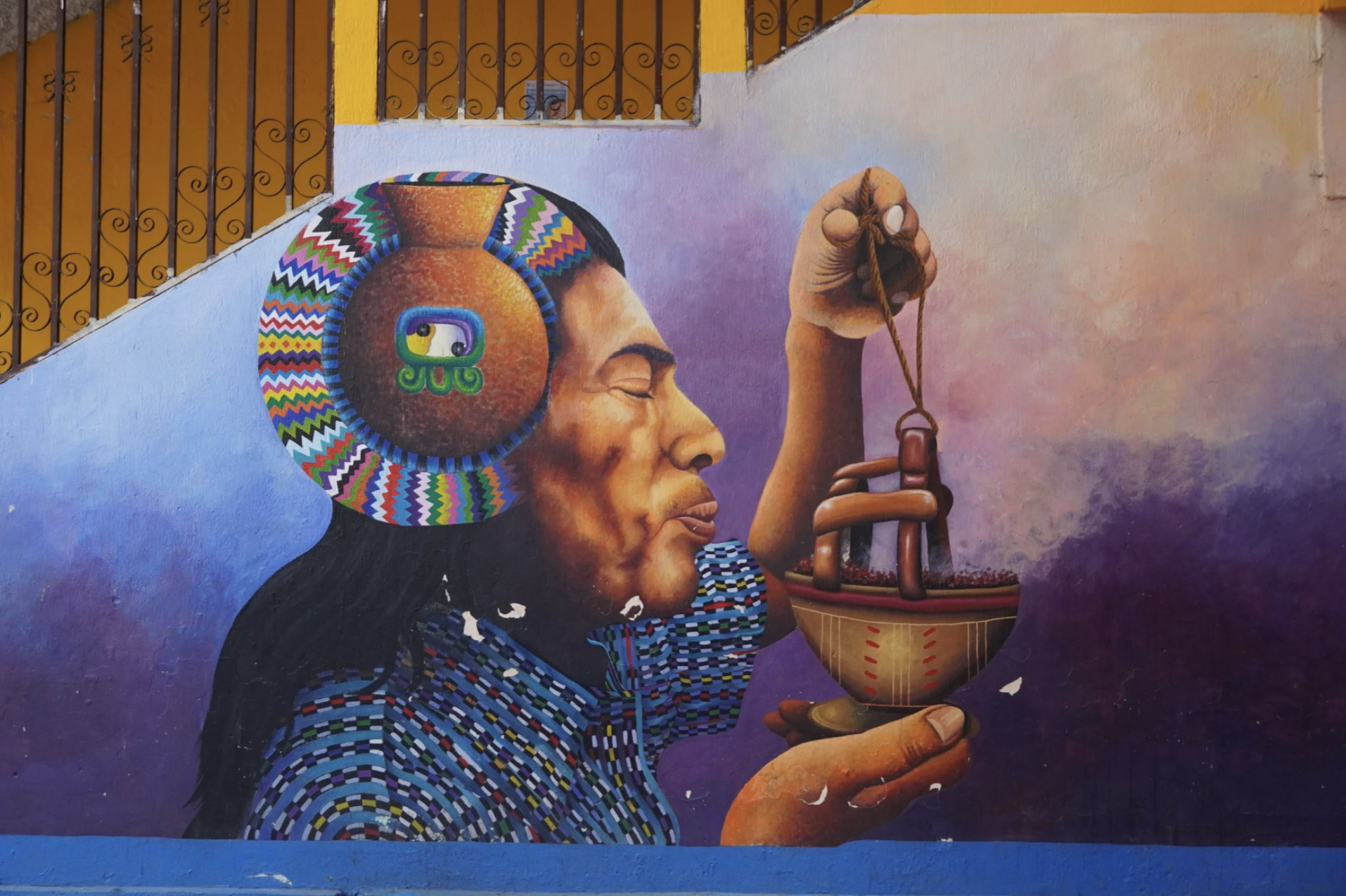 Street art in Guatemala with a Mayan man blowing into a handheld item