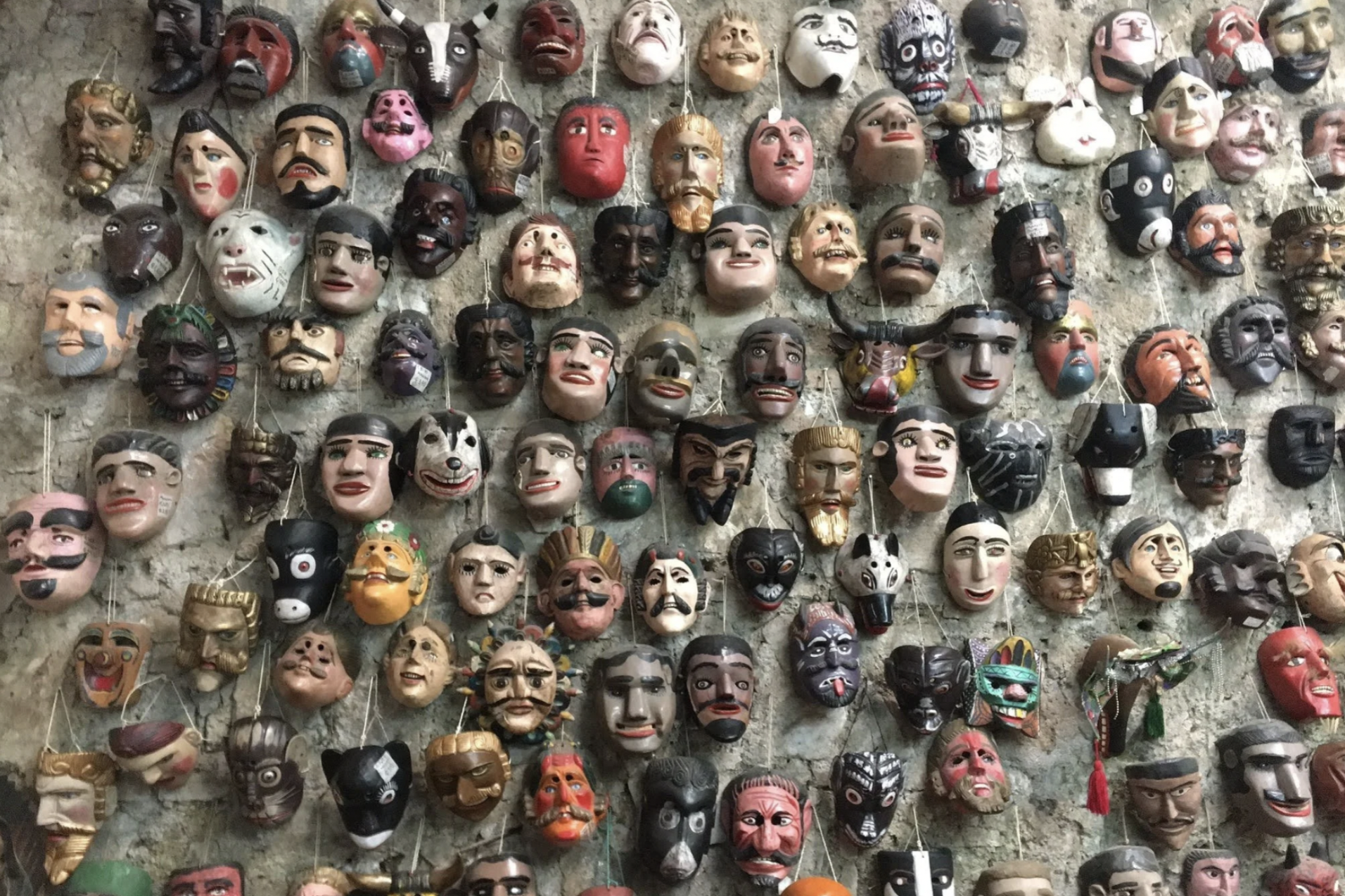 A wall of decorative masks hanging in a shop in Antigua Guatemala