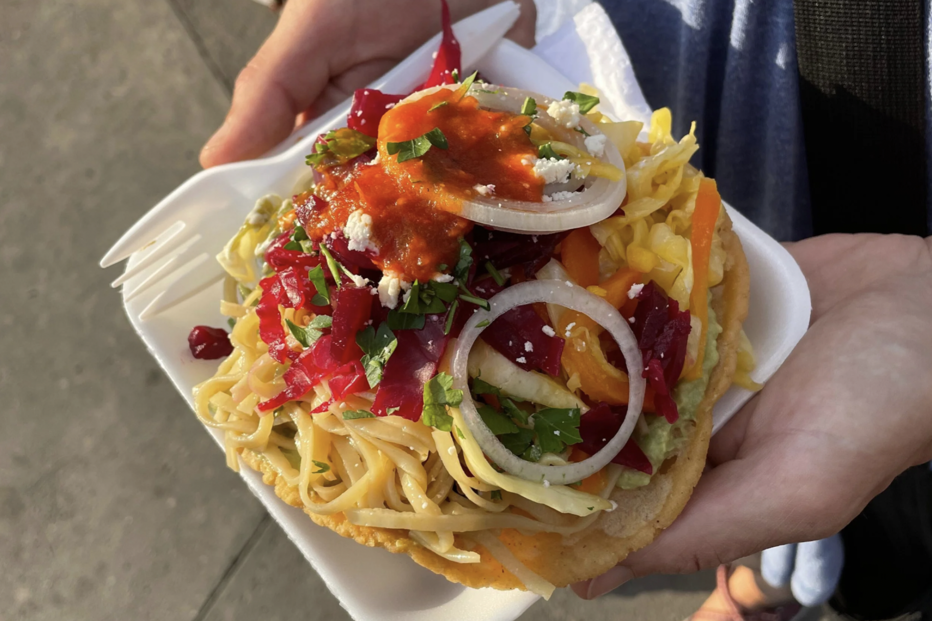 A plate of local street food in Antigua Guatemala with cheese, veggies, and sauce on a tortilla