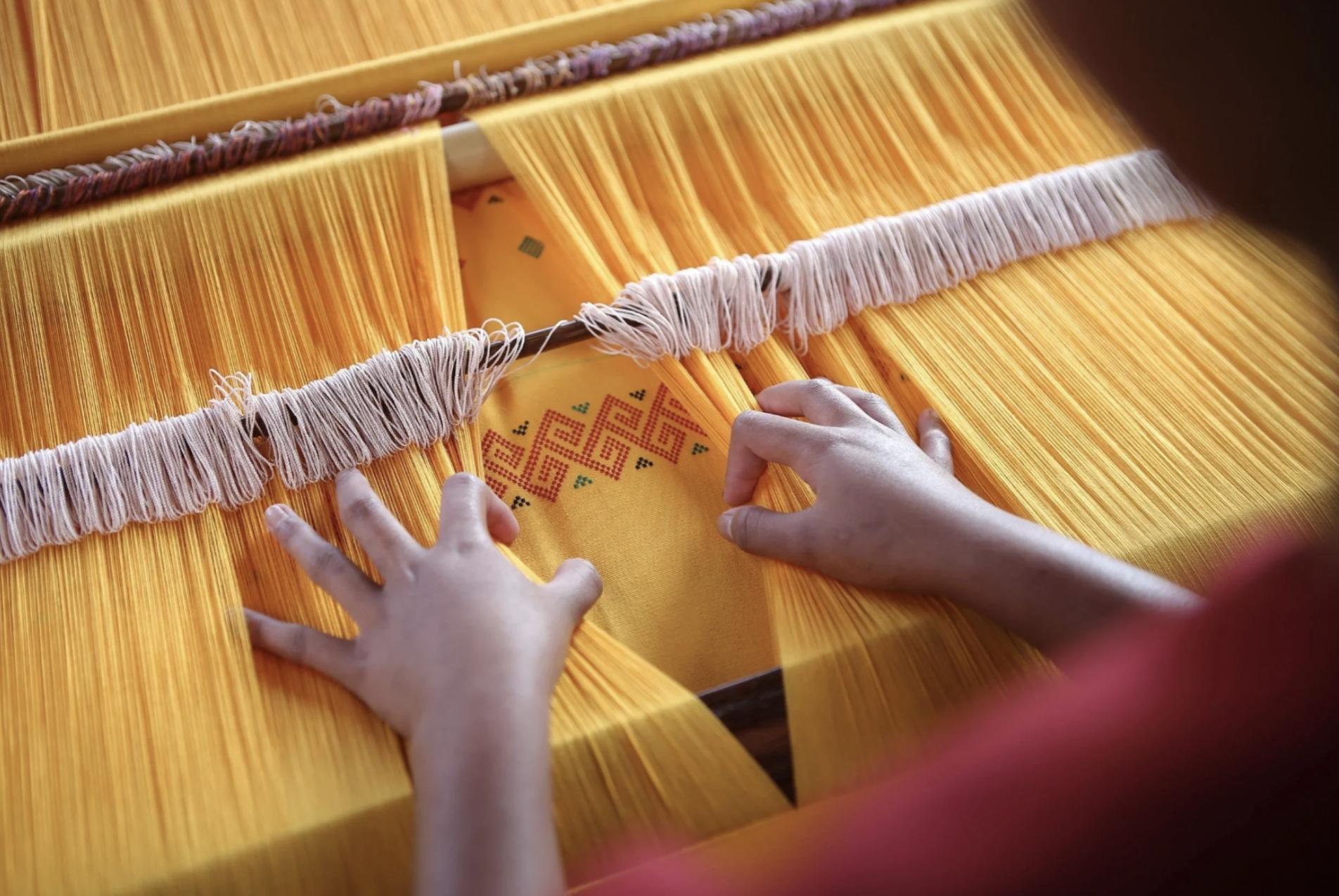 A person is working on a textile in Guatemala using a loom