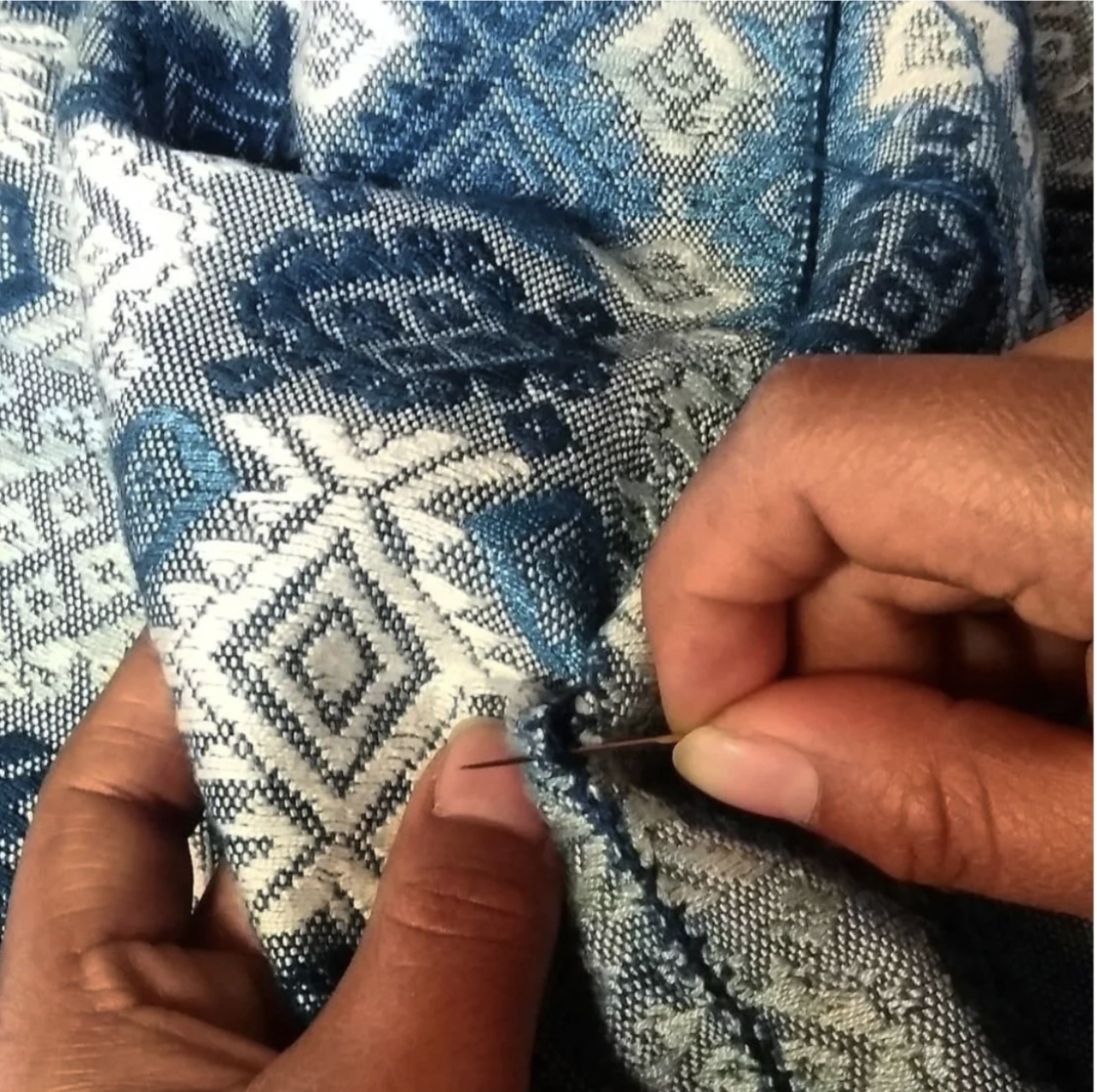 A woman is hand sewing a piece of naturally dyed fabric at the Indigo shop in Antigua, Guatemala.