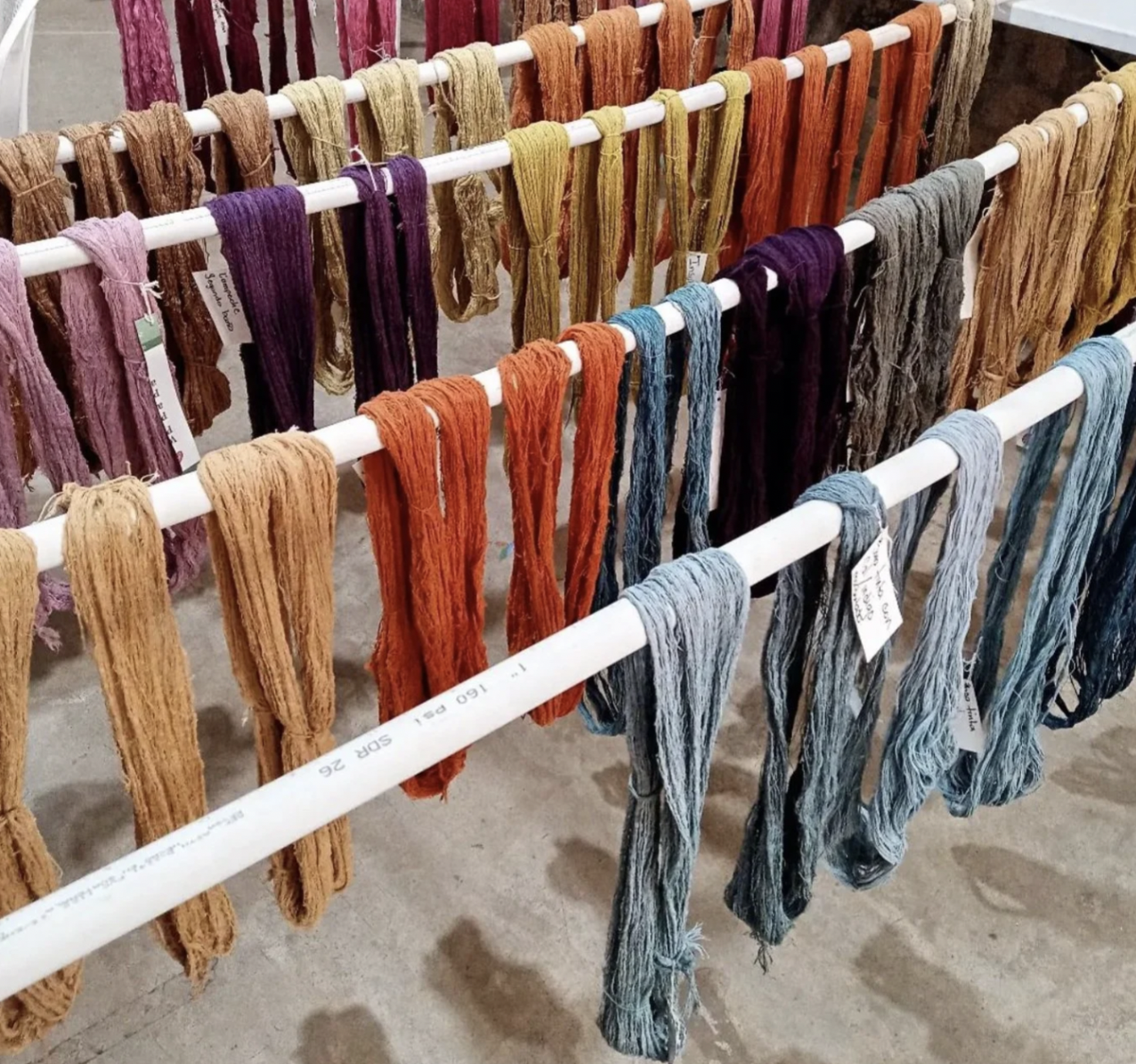 Several batches of naturally dyed fabric are hanging on display in different colors at the Indigo eco-friendly company.