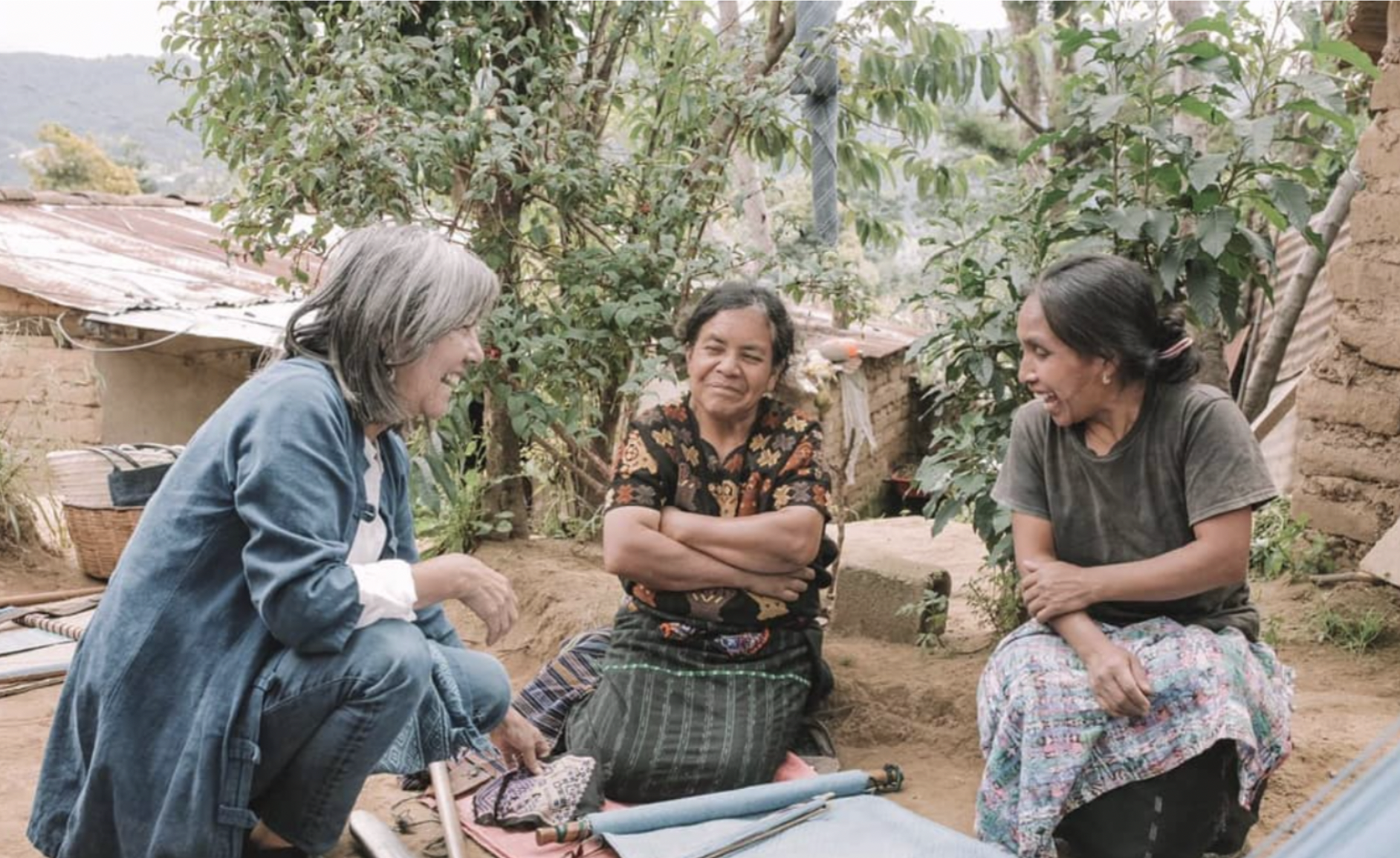 Olga and two women are sitting around fabrics laughing for her natural dye business
