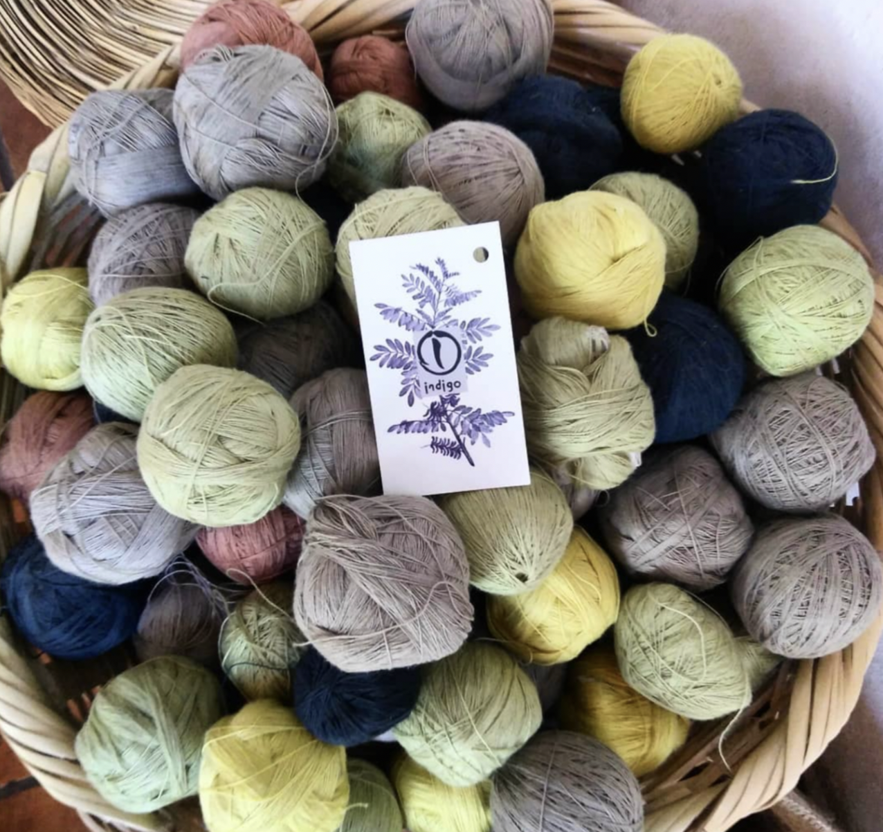 A basket is full of different balls of hand crafted yarn with natural indigo dyes.