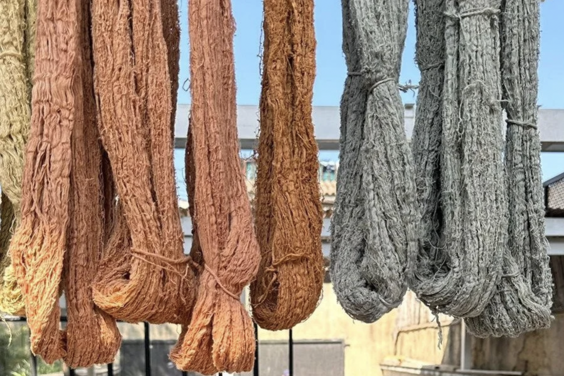 Eight bunches of naturally dyed fabric is hanging on display in Guatemala.