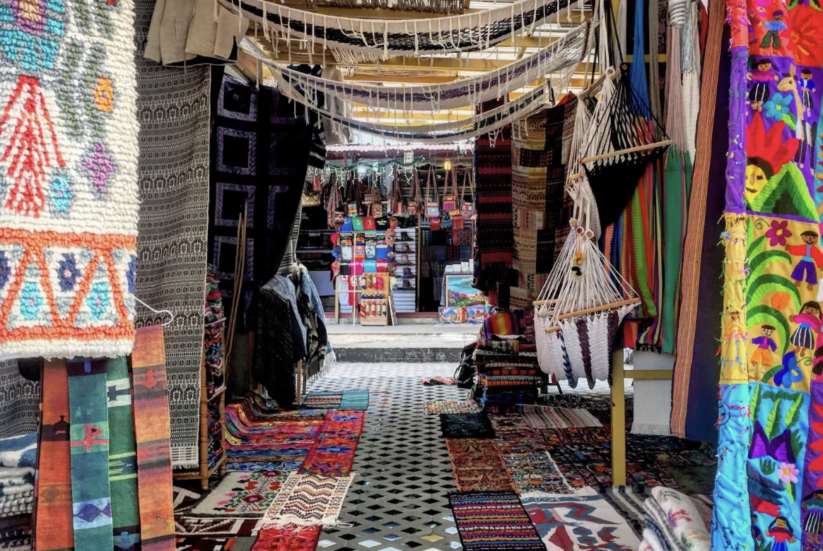 A colorful market in Guatemala is selling textiles, hammocks, rugs, and handicrafts.