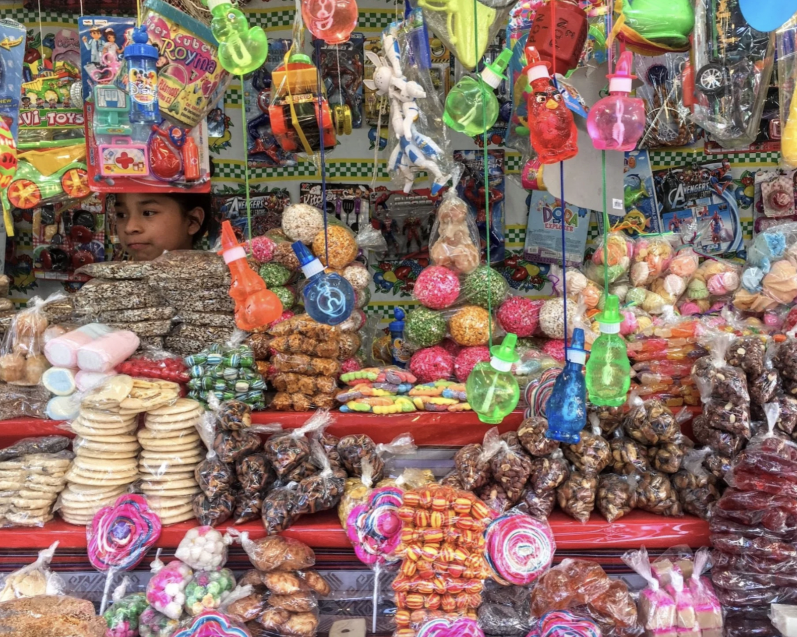 A girl is in a busy stall that's full of candy, snacks, and toys during Semana Santa in Guatemala